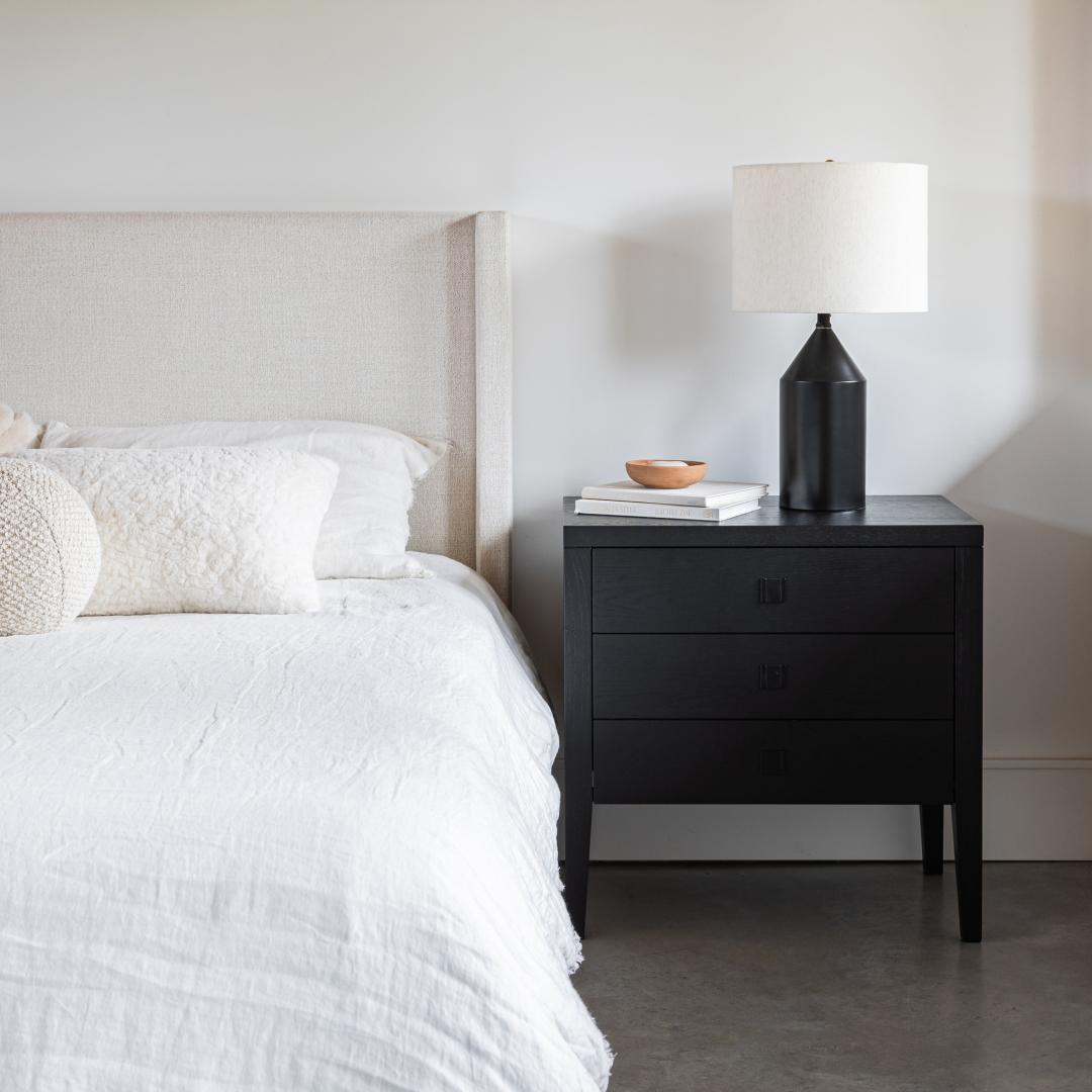 Bedroom with a bed and black nightstand against a white wall