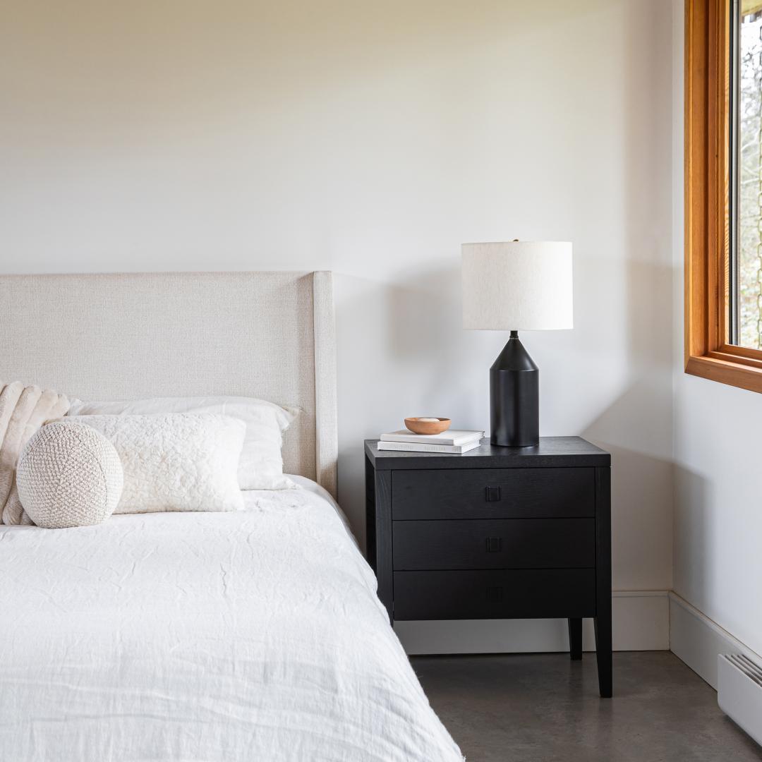 Bedroom with a bed and black nightstand featuring a lamp.