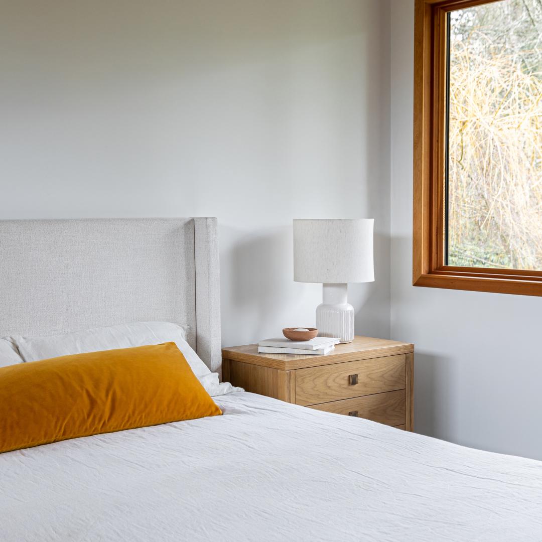 Bedroom with a bed, nightstand, and lamp near a window.
