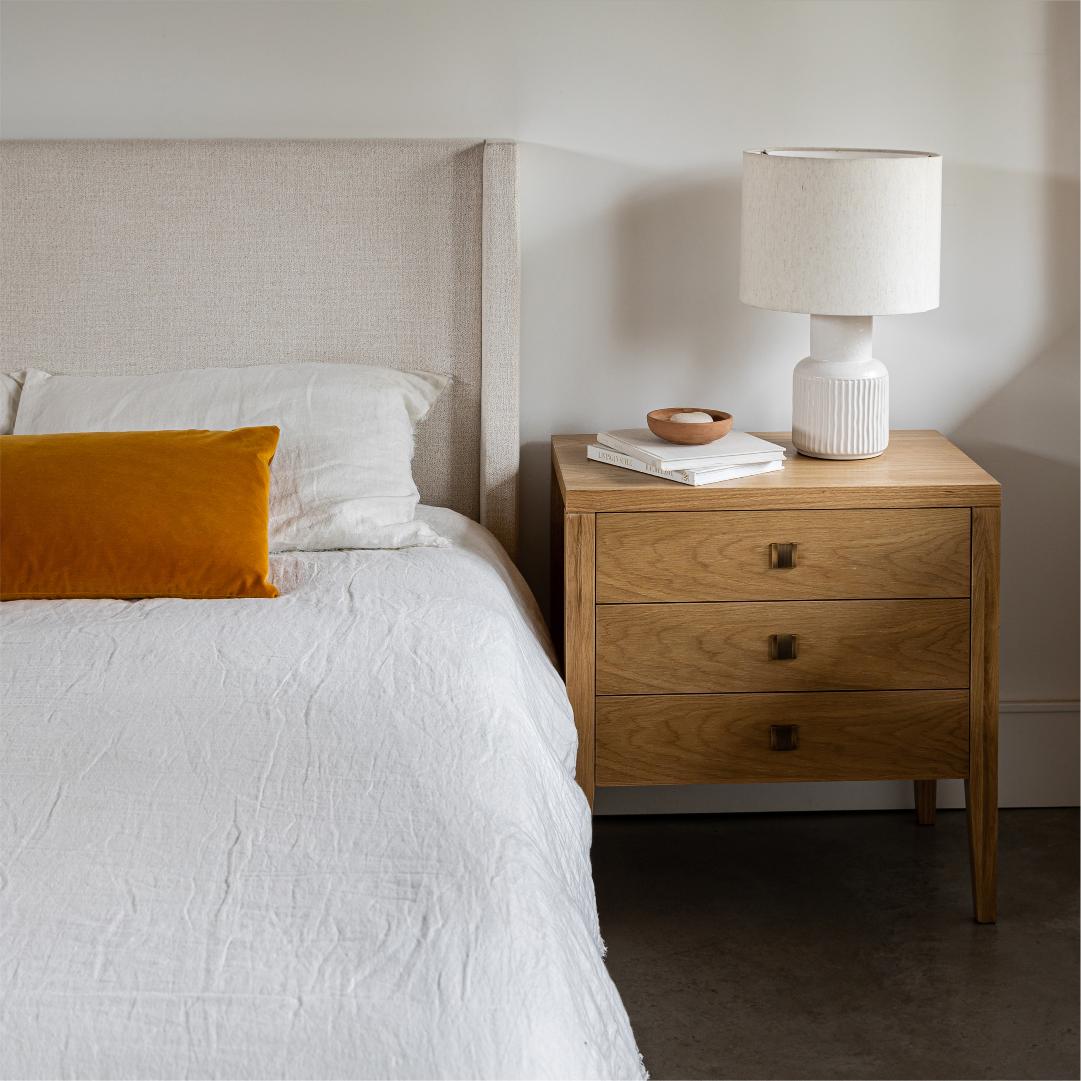 Bedroom with a bed and wooden nightstand featuring a lamp.