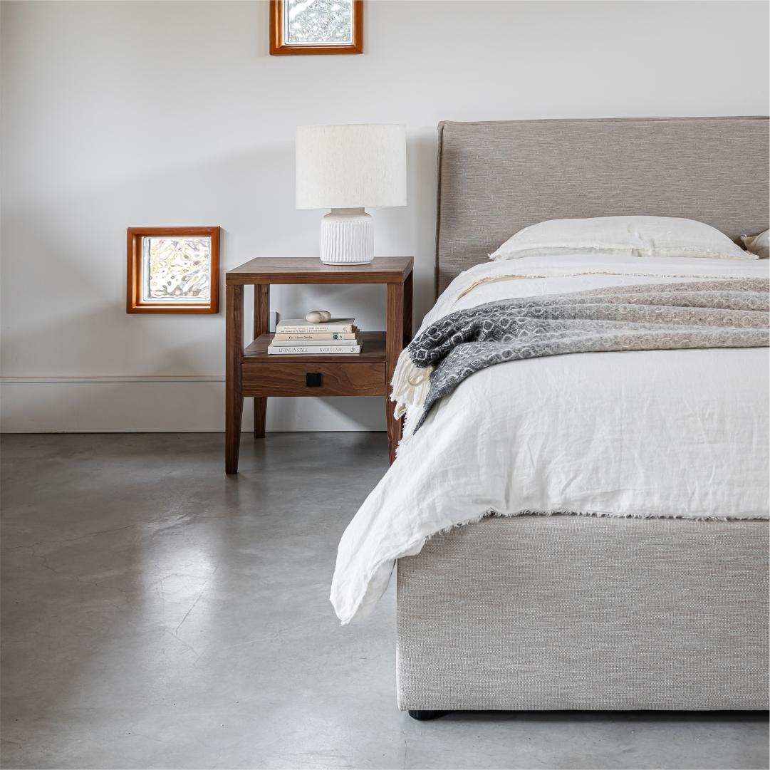 Bedroom with a bed, nightstand, and lamp in a neutral color scheme.