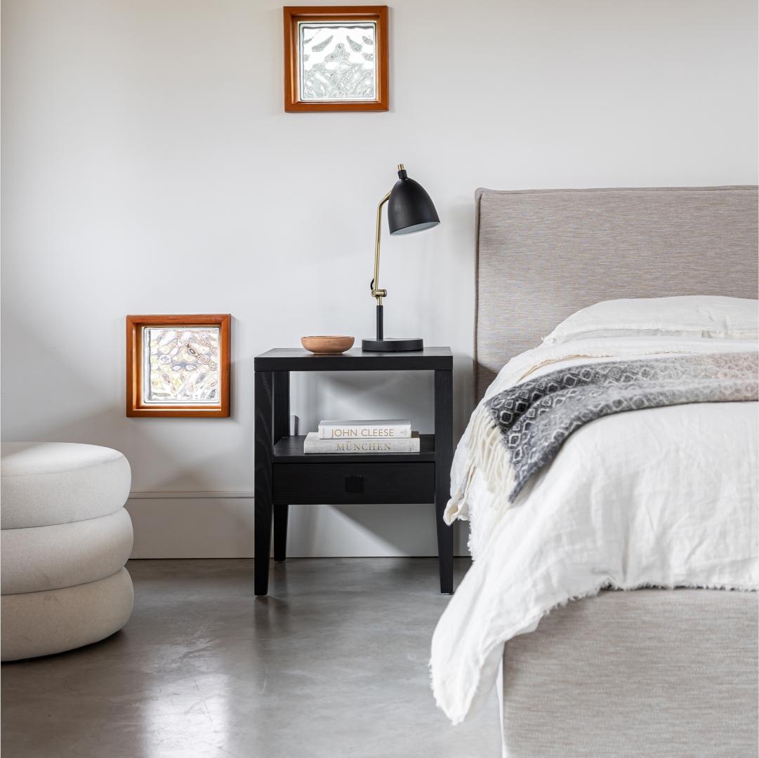 Modern bedroom with a bed, nightstand, and decorative elements.