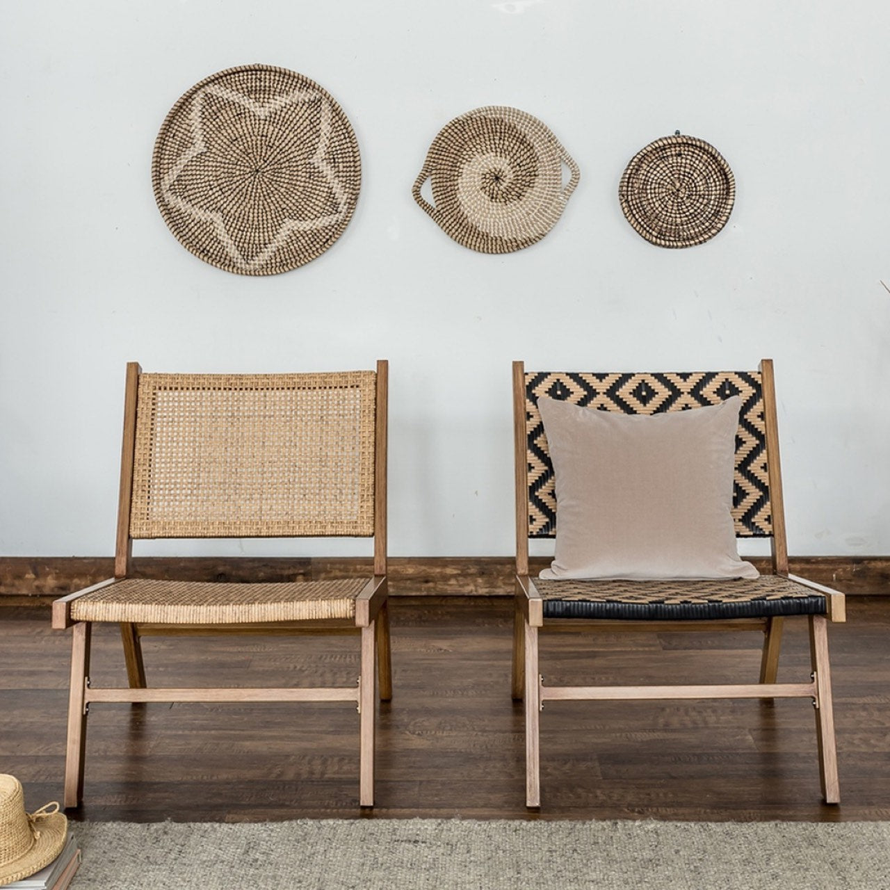 Two wooden chairs with woven backrests and a pillow, wall with decorative baskets in the background.