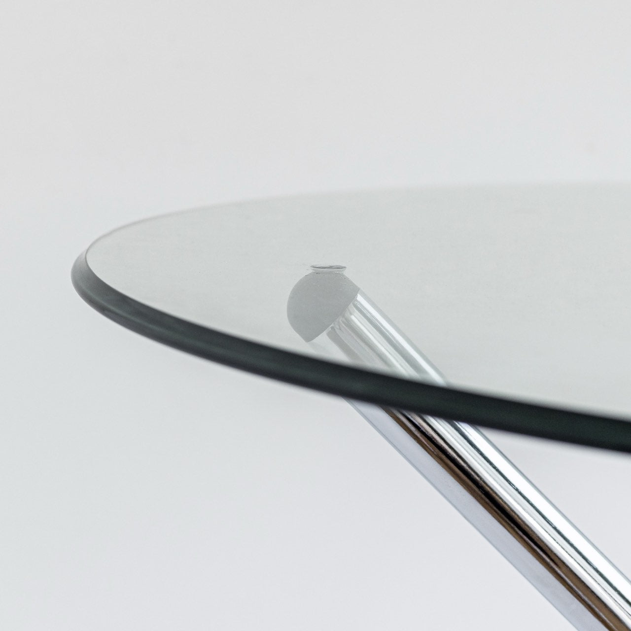 Close-up of a glass table with metal legs on a light gray background