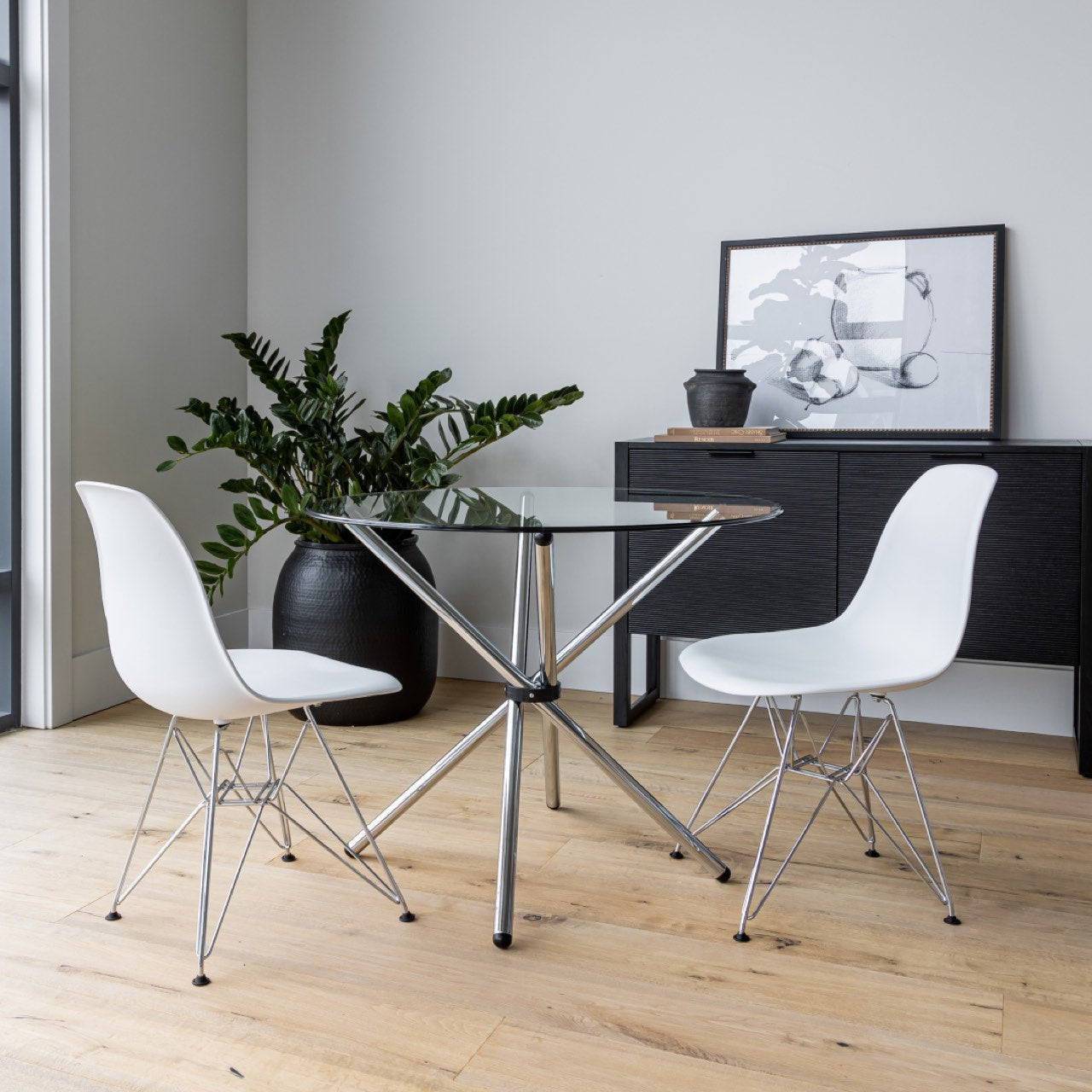 Modern glass dining table with white chairs in a minimalistic room.