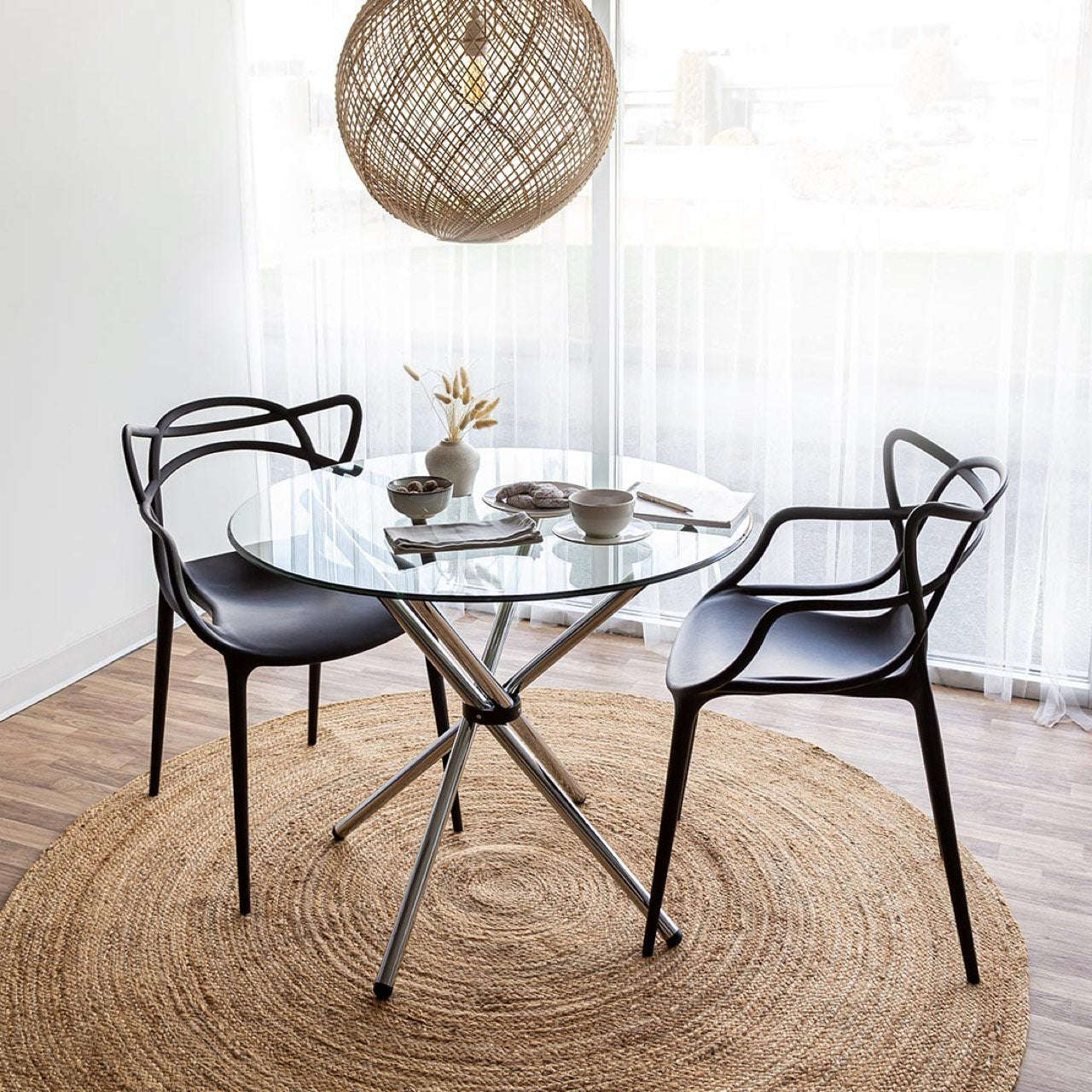 Modern dining set with glass table and black chairs on a wooden floor.