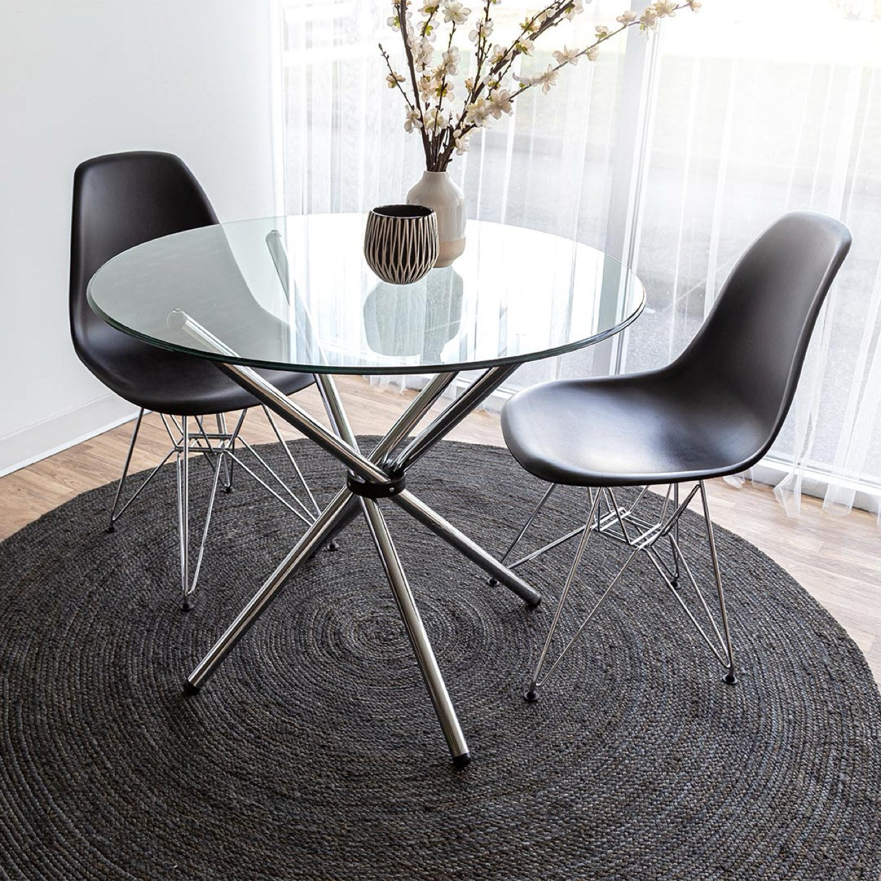 Modern glass dining table with black chairs on a dark rug
