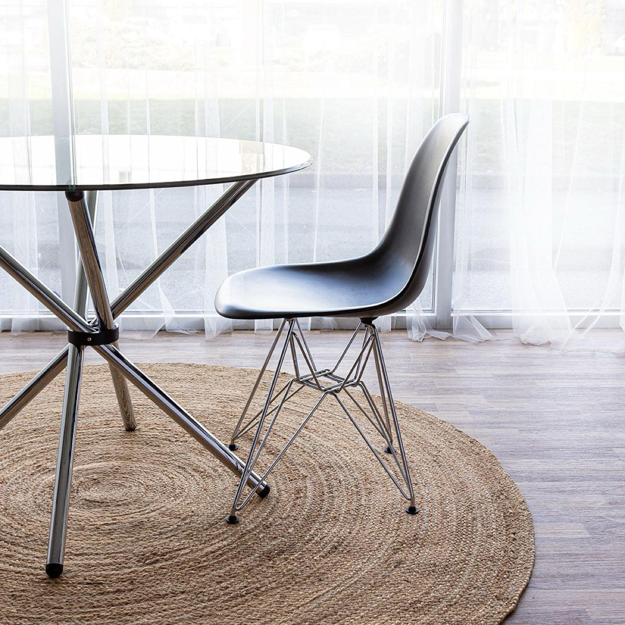 Modern glass dining table with a chair on a wooden floor in a bright room.