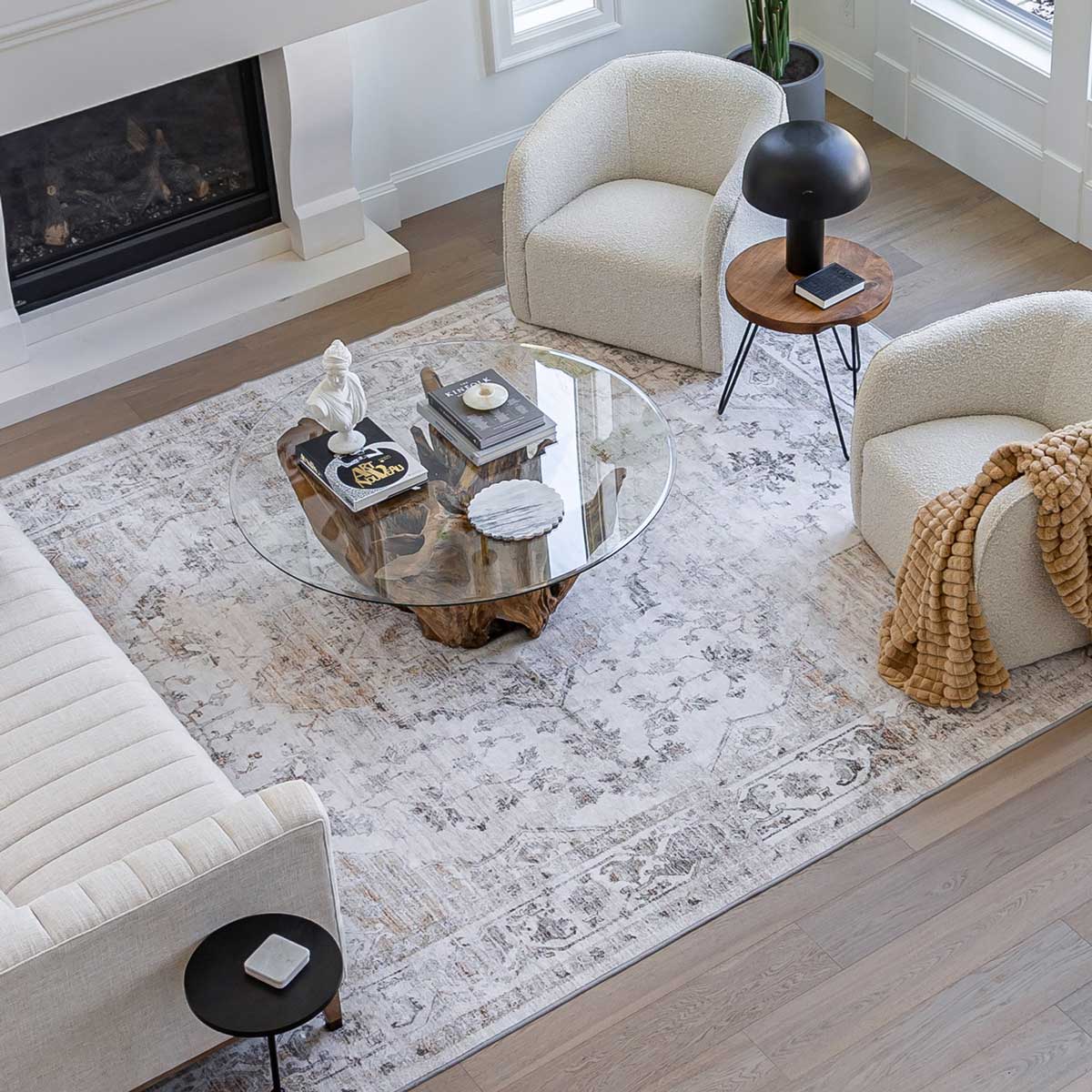 Living room with a glass coffee table, armchairs, and a fireplace.