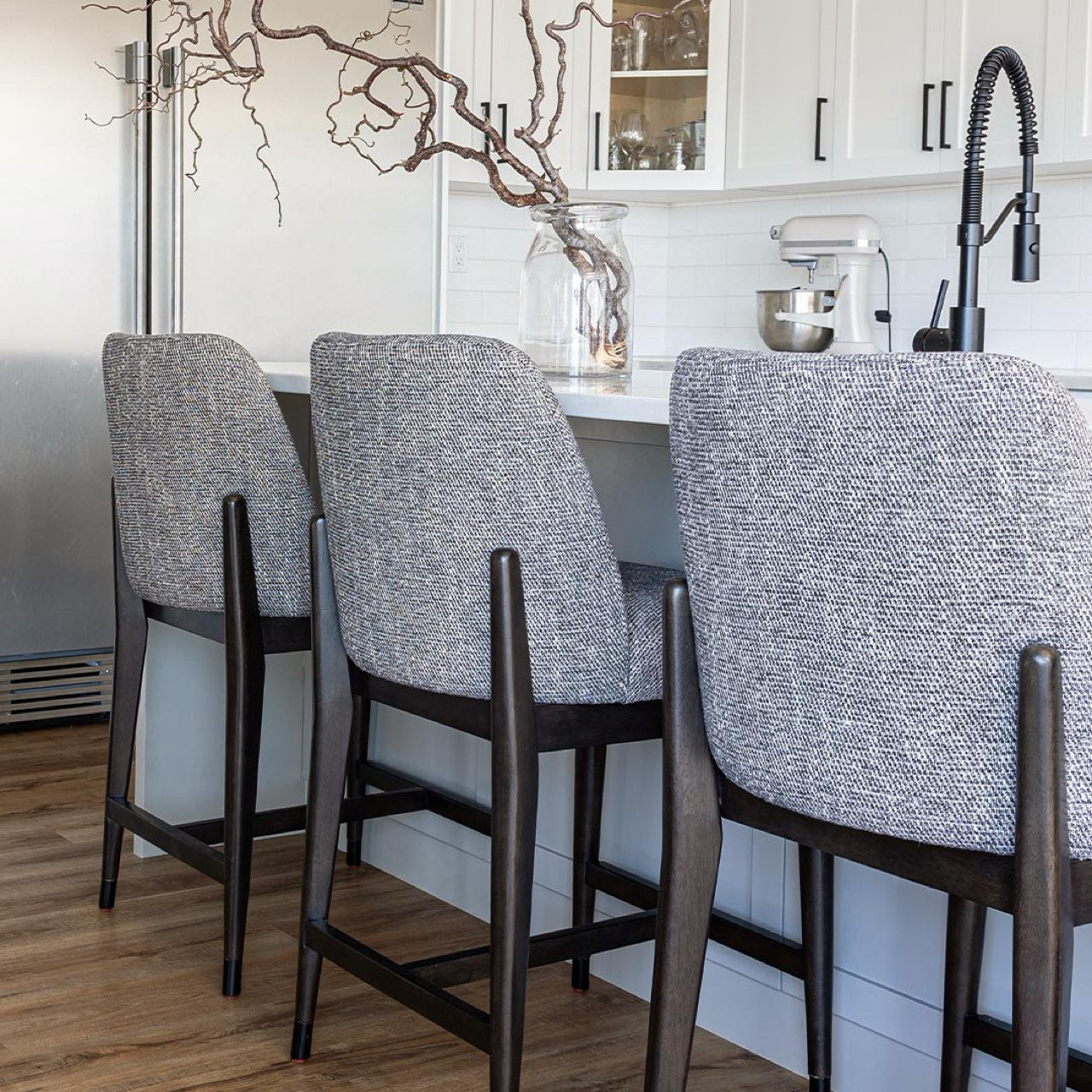 Gray bar stools in a modern kitchen setting with white cabinets and a black faucet.
