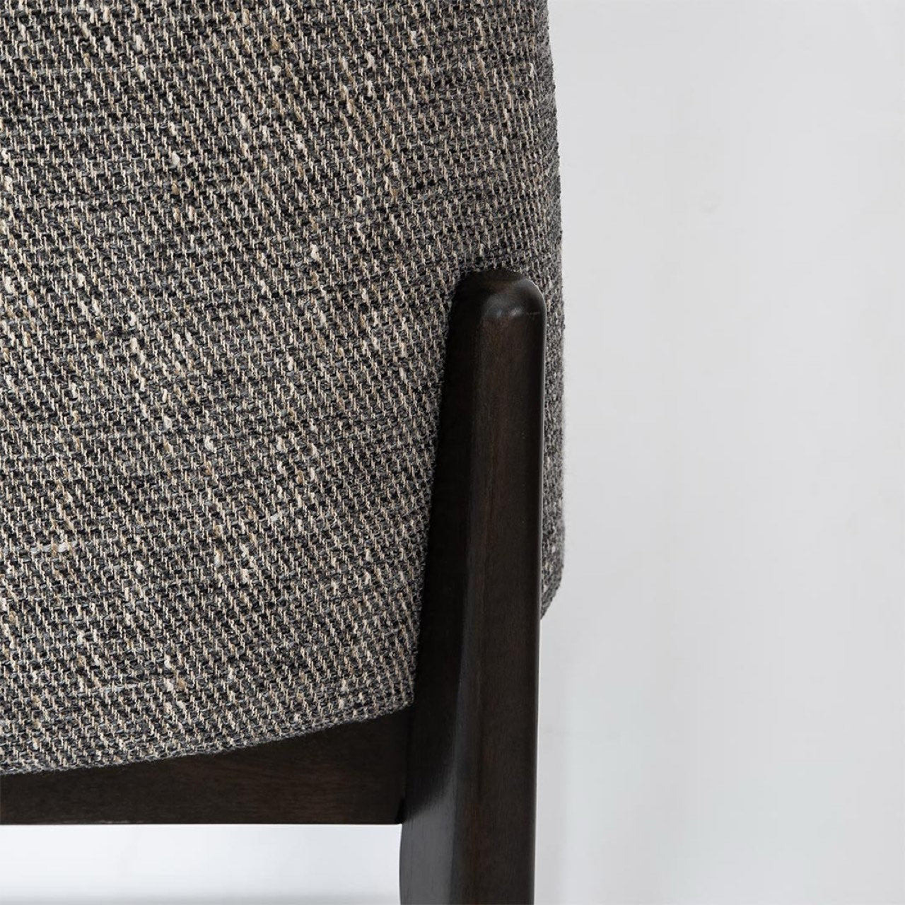 Close-up of a textured gray chair backrest with dark wooden armrest on a light gray background