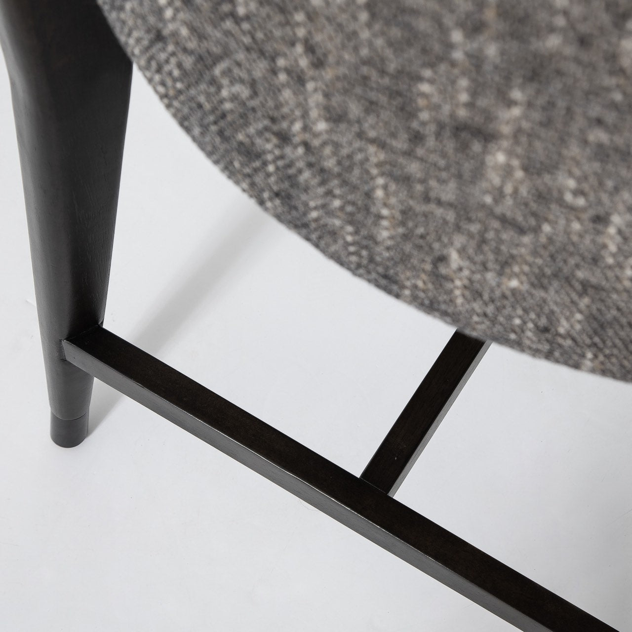 Close-up of a chair with a textured gray cushion and black metal frame on a white background