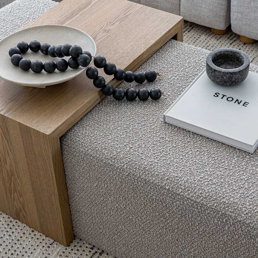 Decorative elements on a wooden side table including beads, a bowl, and a book titled 'STONE'.