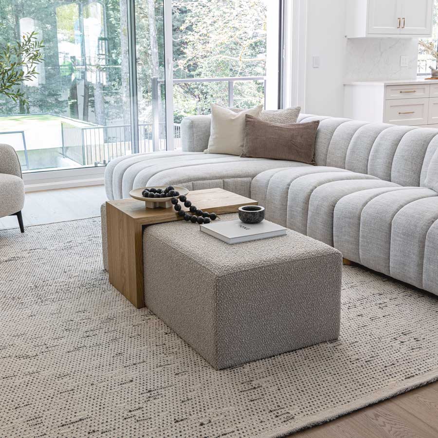 Modern living room with a gray sectional sofa, ottoman, and coffee table.