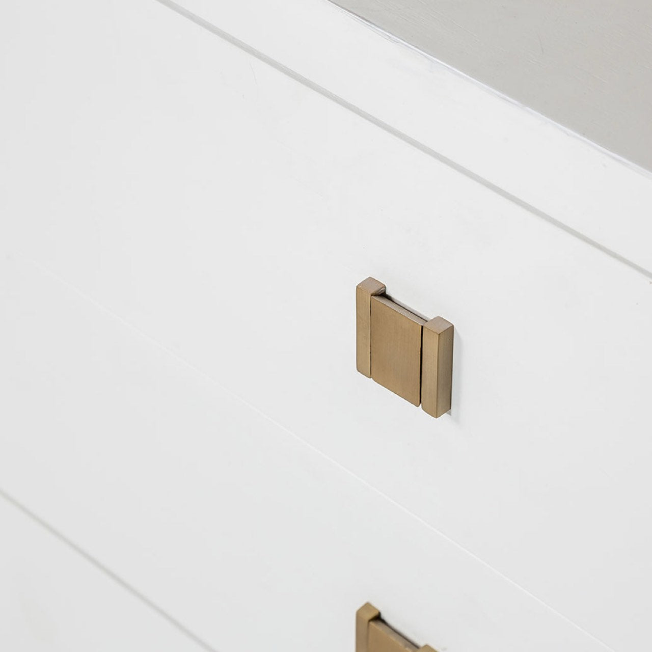 Gold cabinet handle on a white drawer