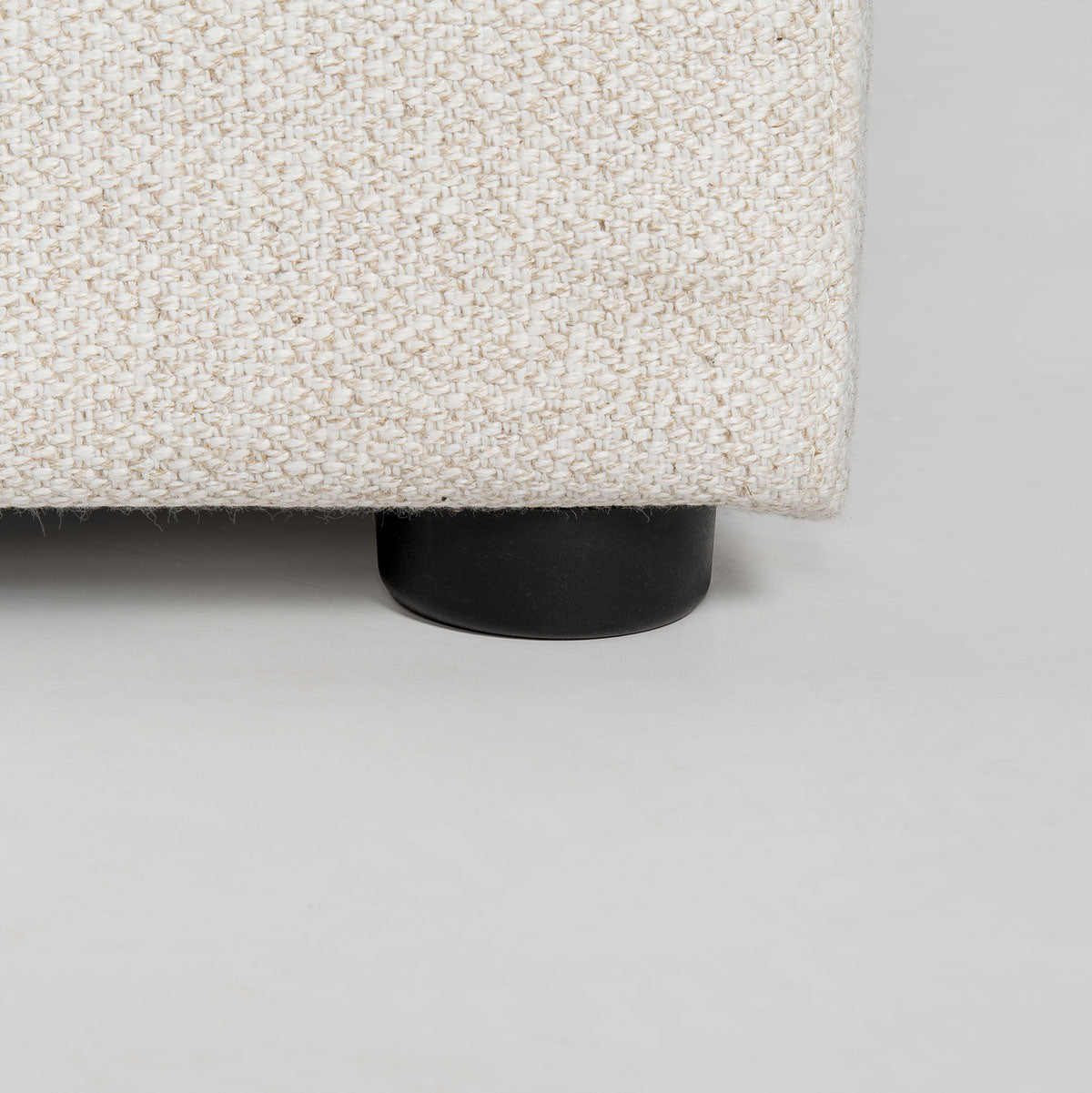 Close-up of a textured fabric surface with a black leg on a gray background