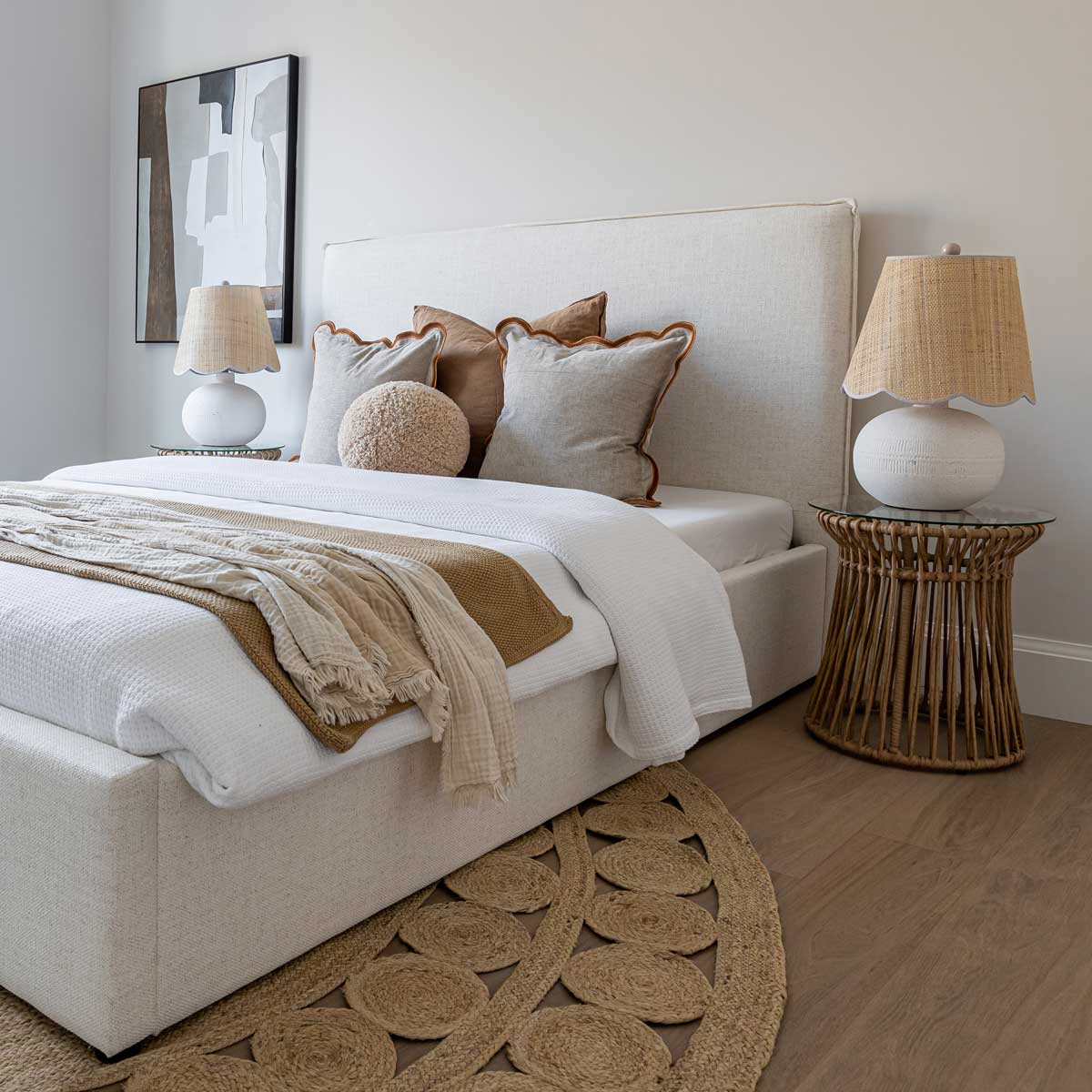 Neatly made bed with decorative pillows and lamps in a bedroom setting.