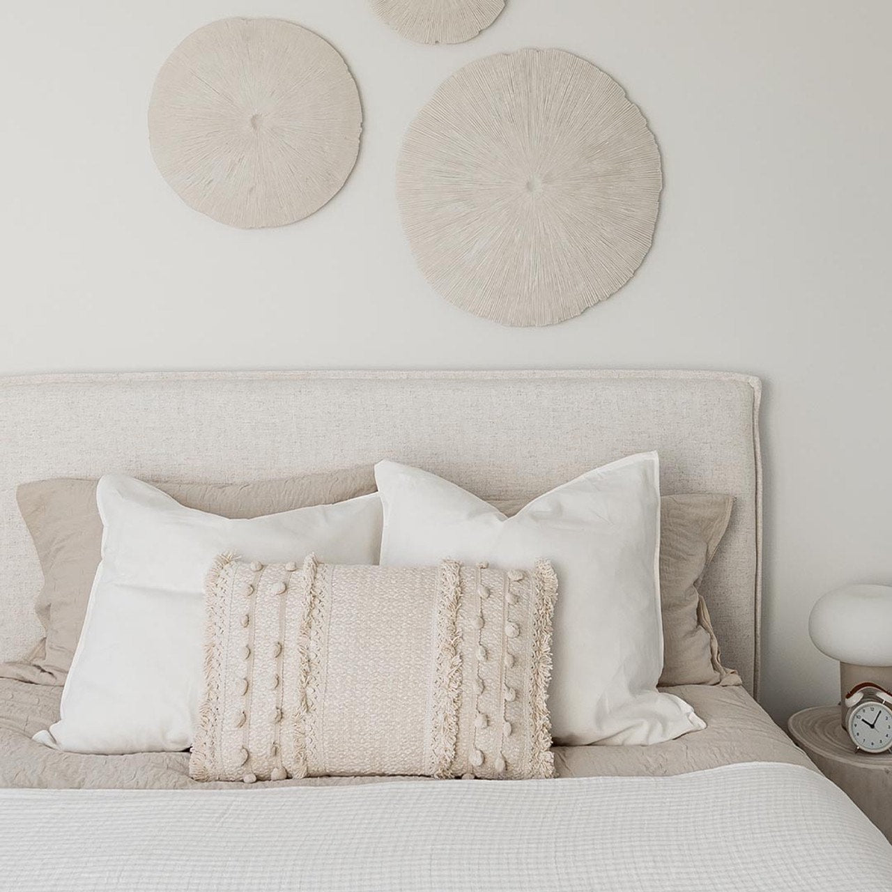 Neatly made bed with decorative pillows and wall art in a bedroom setting