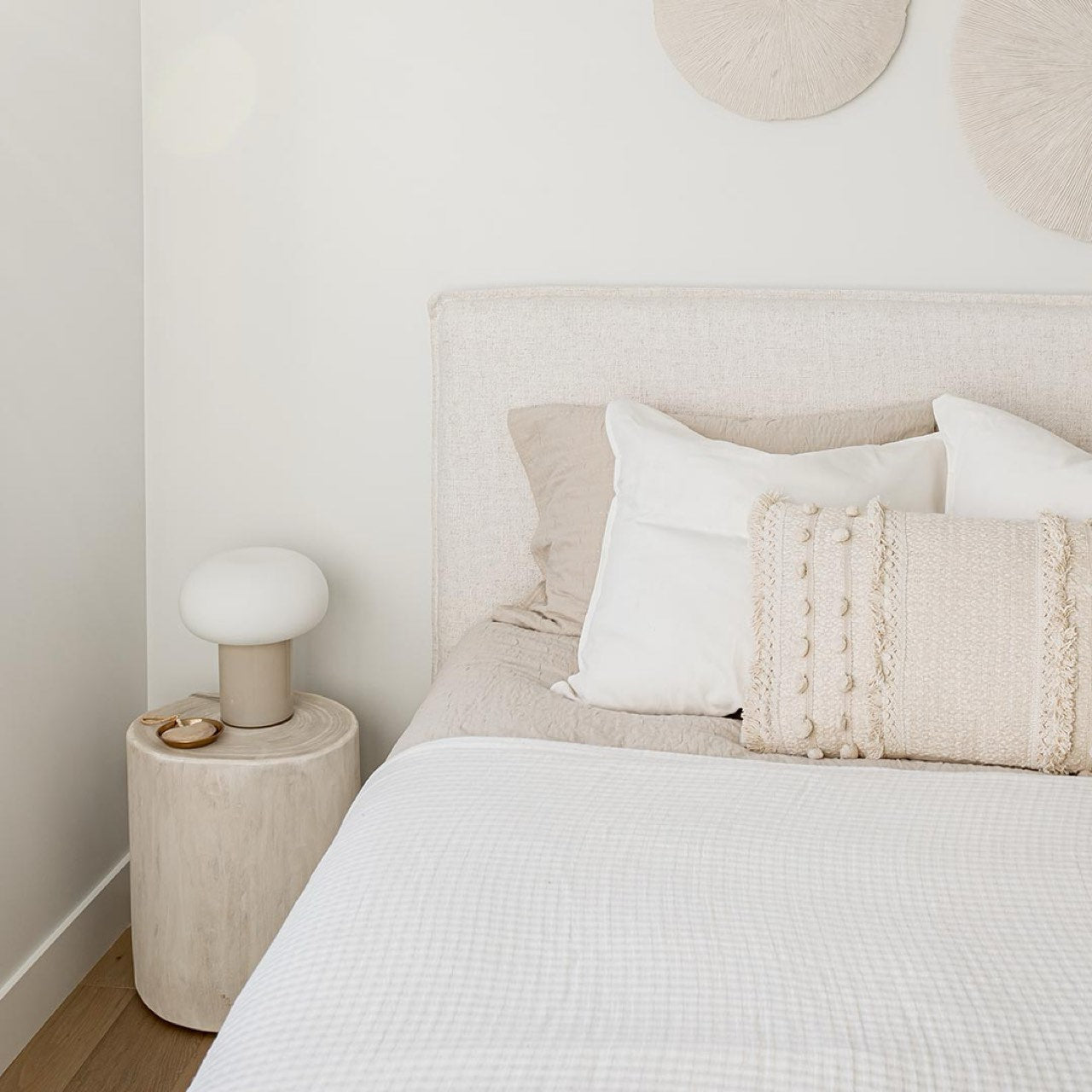 Neatly made bed with white bedding and decorative pillows in a bedroom setting.