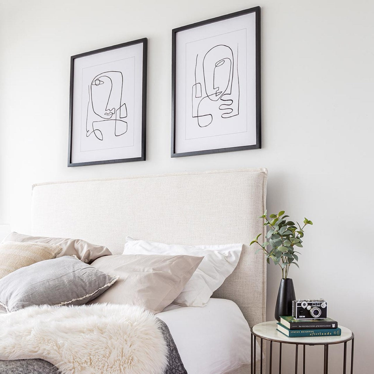 Modern bedroom with abstract wall art and a side table.