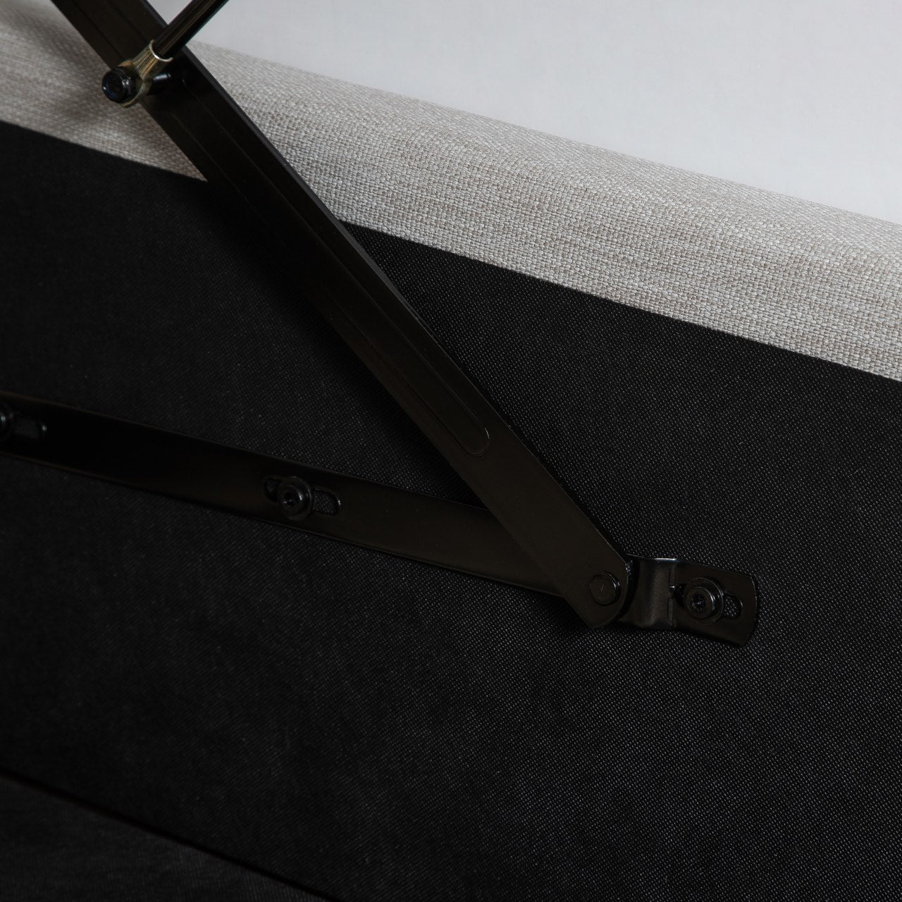 Close-up of a black metal bracket on a gray and black fabric surface.
