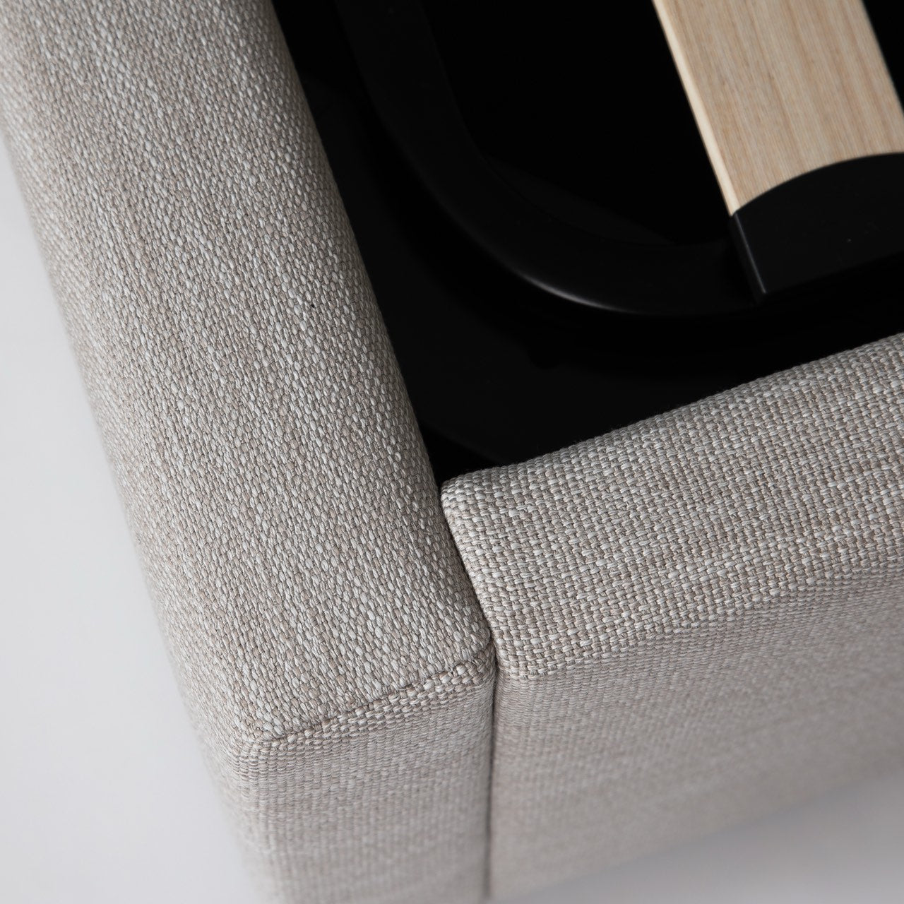 Close-up of a textured gray fabric corner with a black base and wooden element.