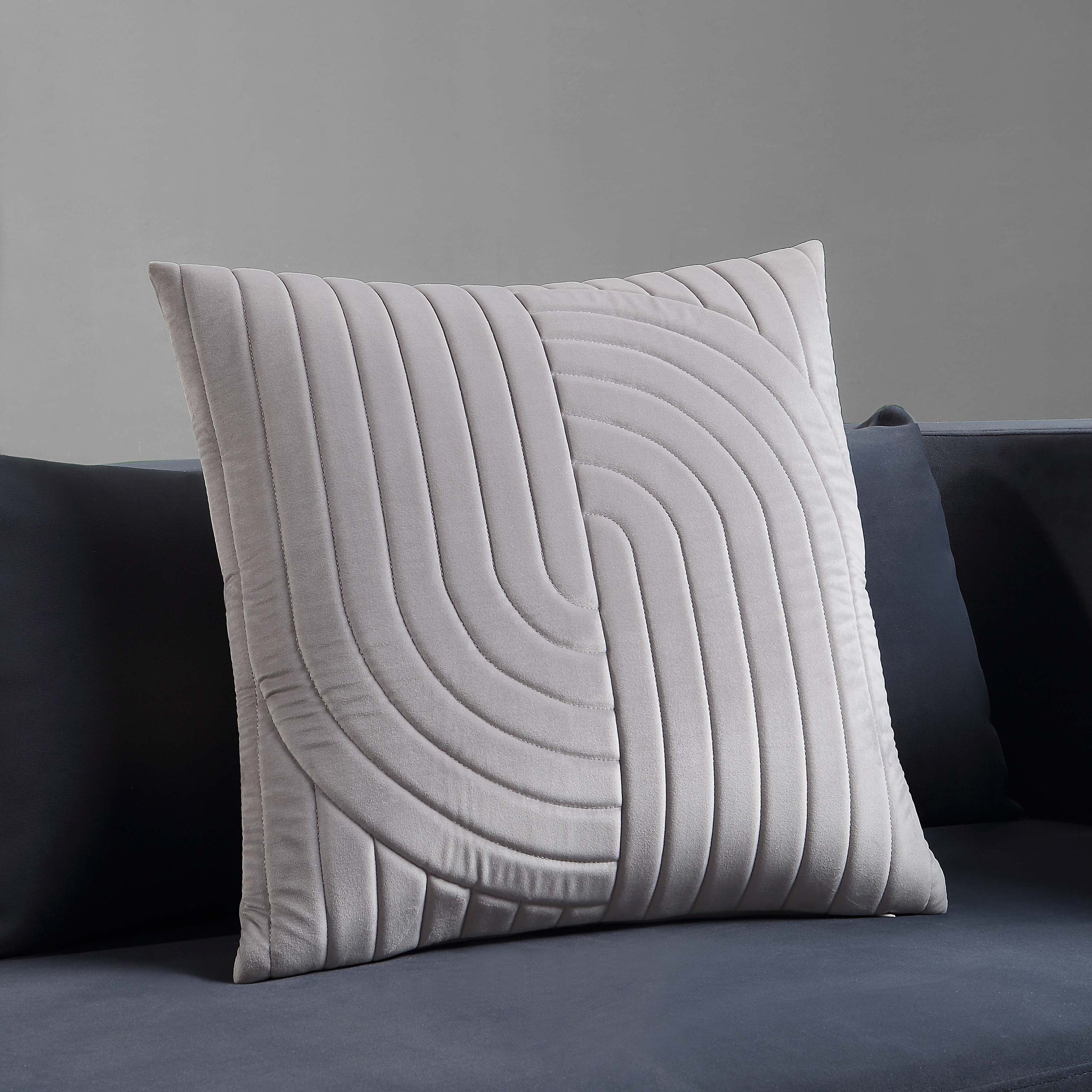 Ultar Indoor Pillow in light gray displayed on a dark sofa.