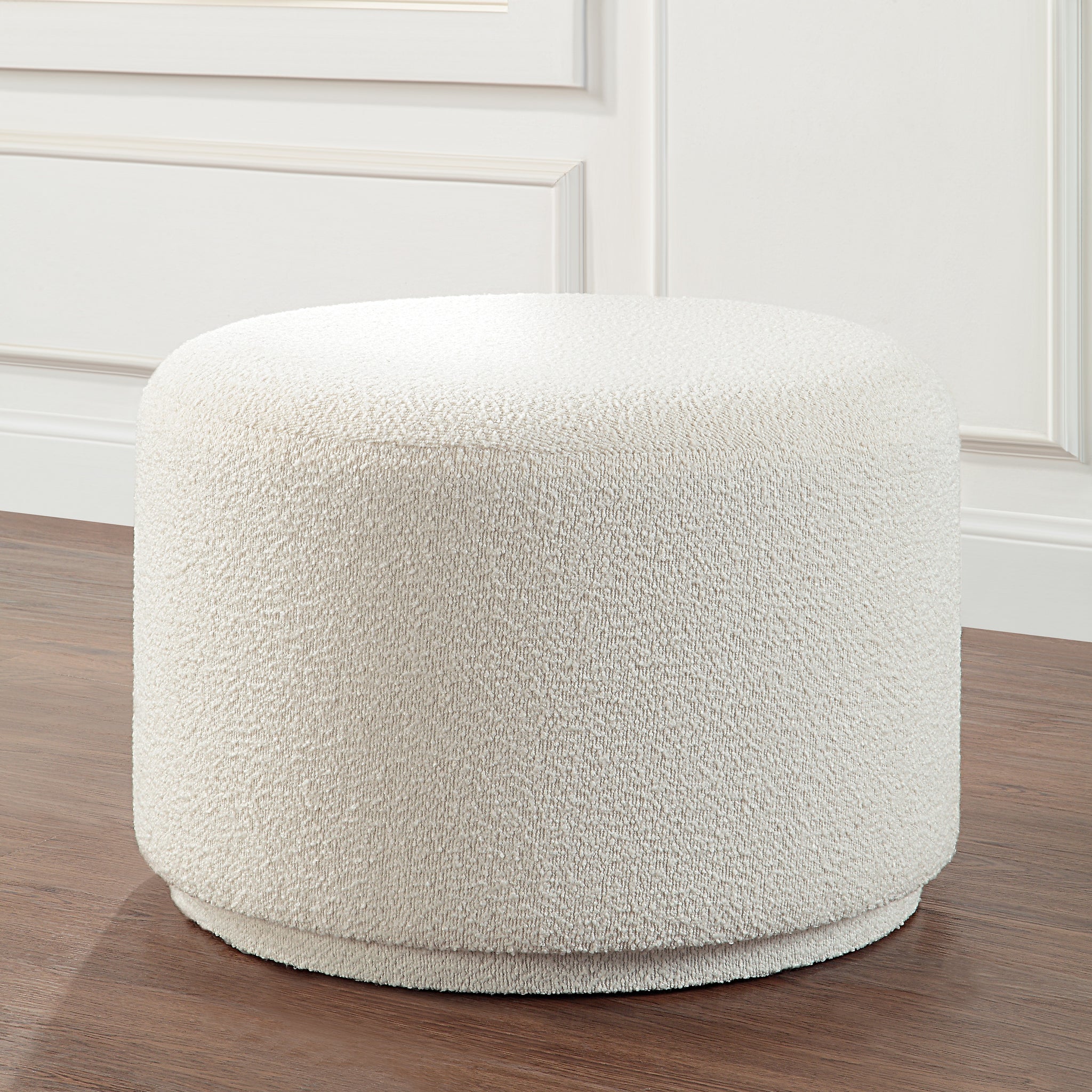 Audrina Ottoman with a soft white texture, round shape, placed in a room setting
