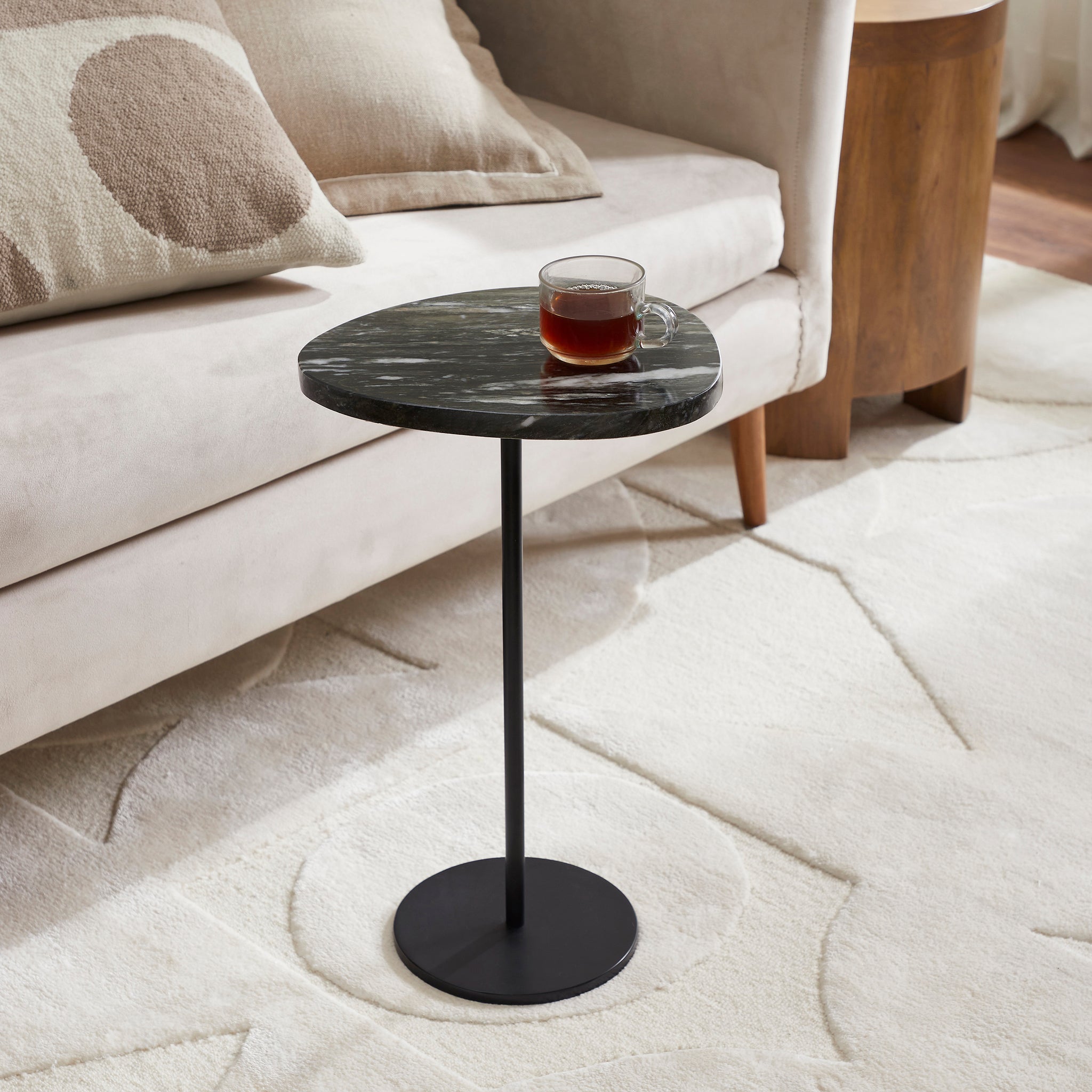 Adeline Side Table beside a sofa, holding a cup of tea, highlighting its practical use.