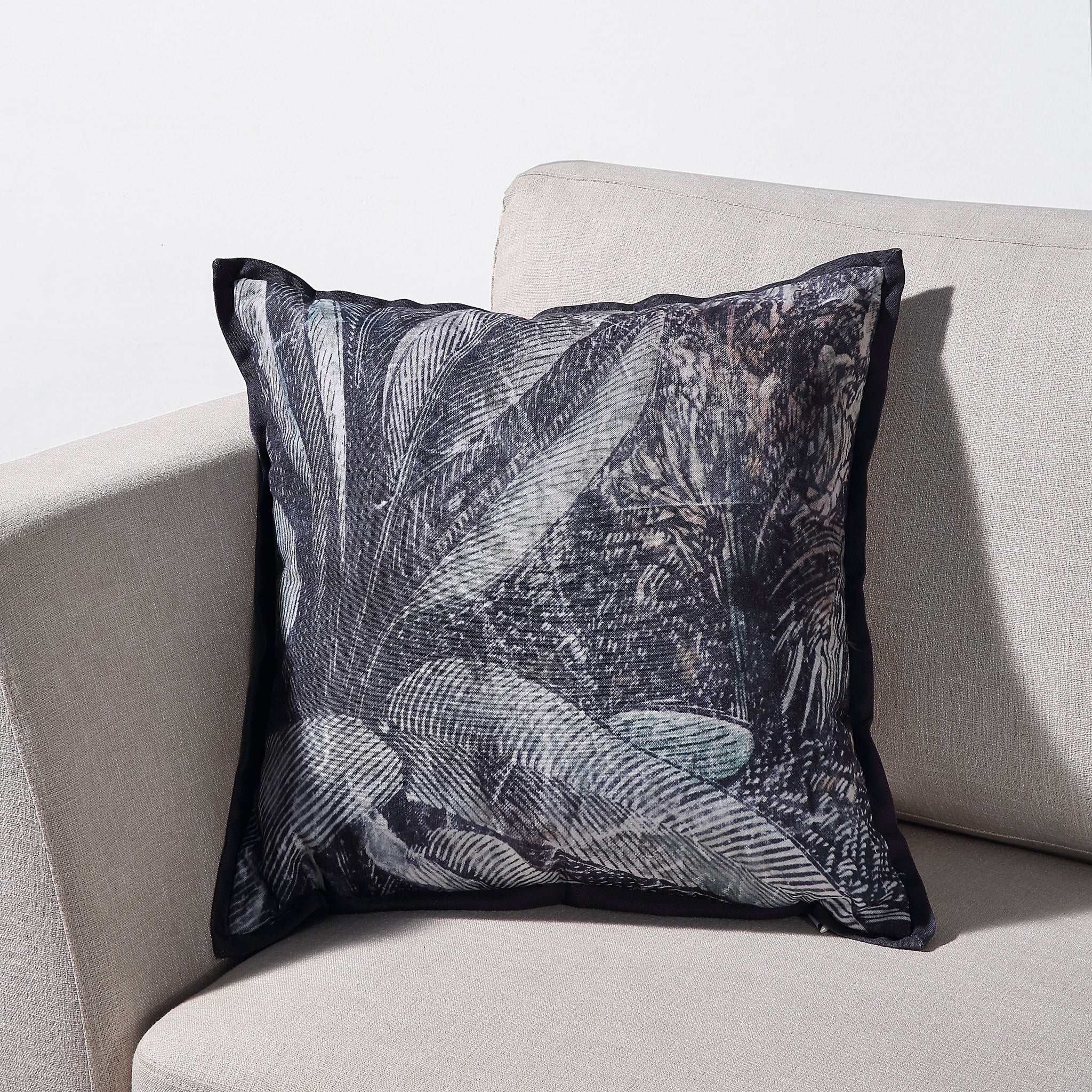 Mangrove Indoor Pillow on a sofa, featuring a lush palm leaf design with a dark border.