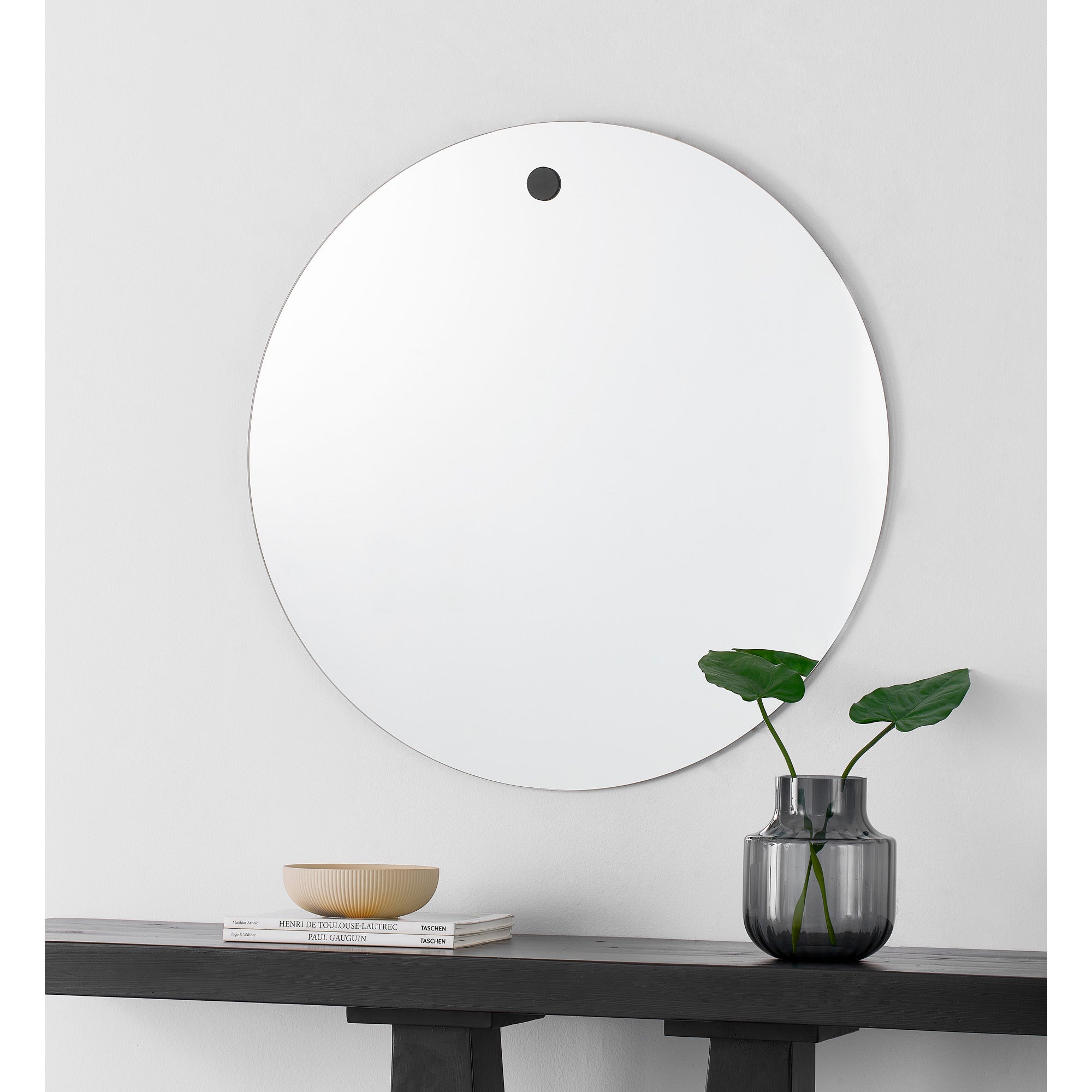 Zachary Wall Mirror mounted on a wall above a table with a vase and decor.