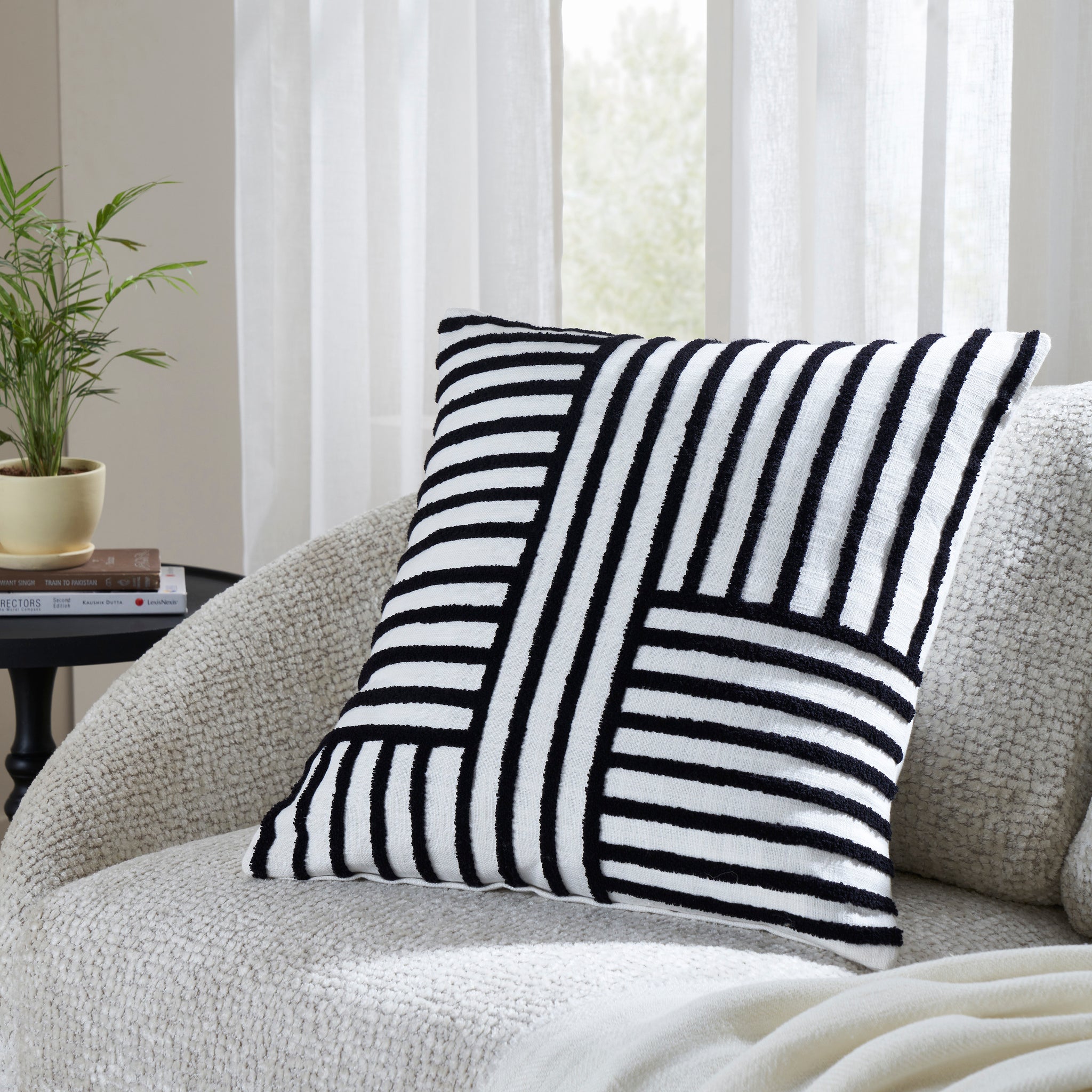 Stilo indoor pillow with a black and white striped design, placed on a cozy sofa.