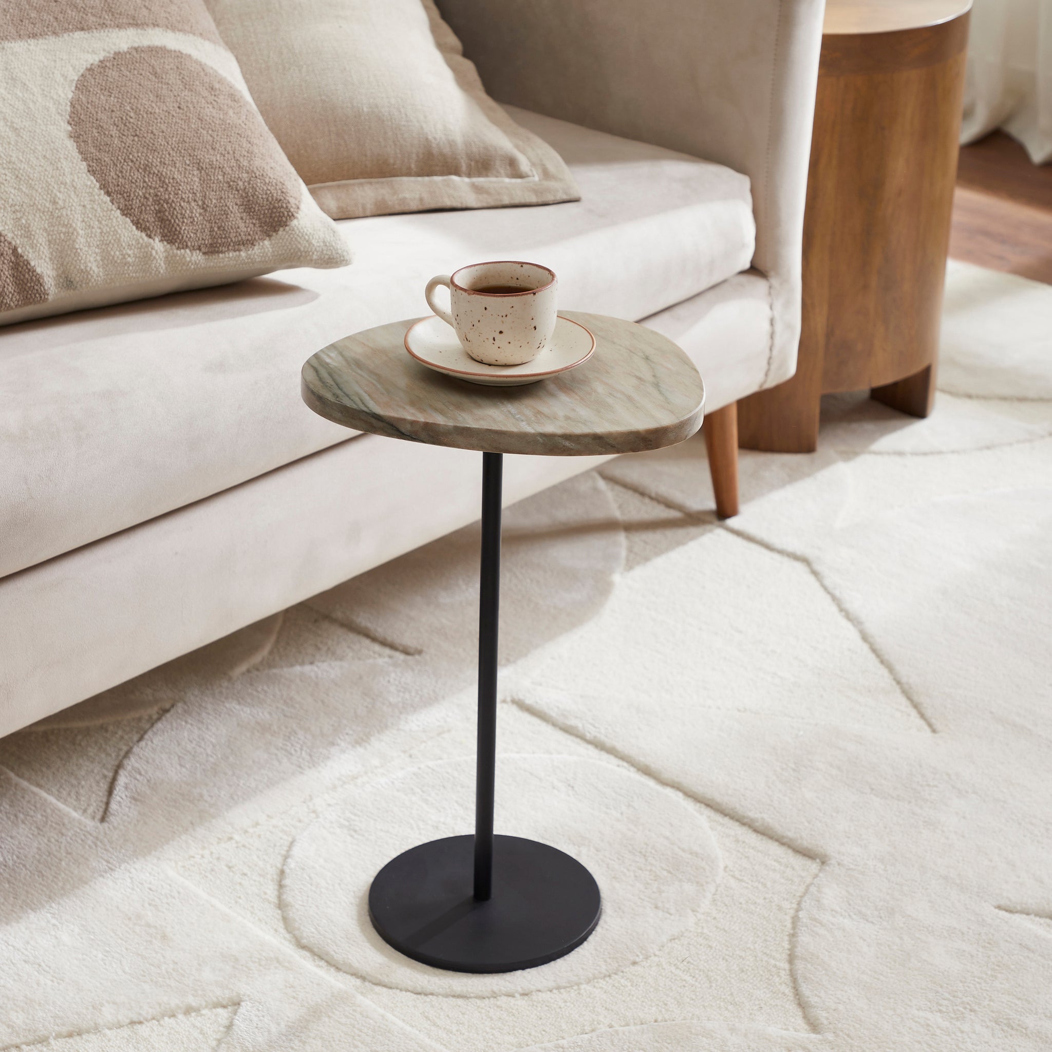 Bethany Side Table beside a sofa, holding a cup on its marble top, in a cozy living room setting.
