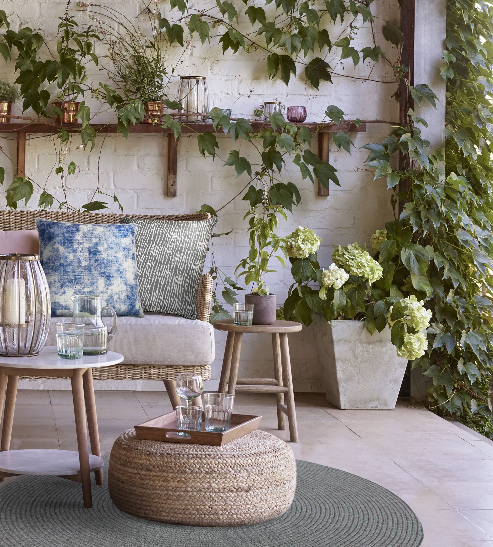 Skye pillow in blue placed on a cozy outdoor seating area with greenery.