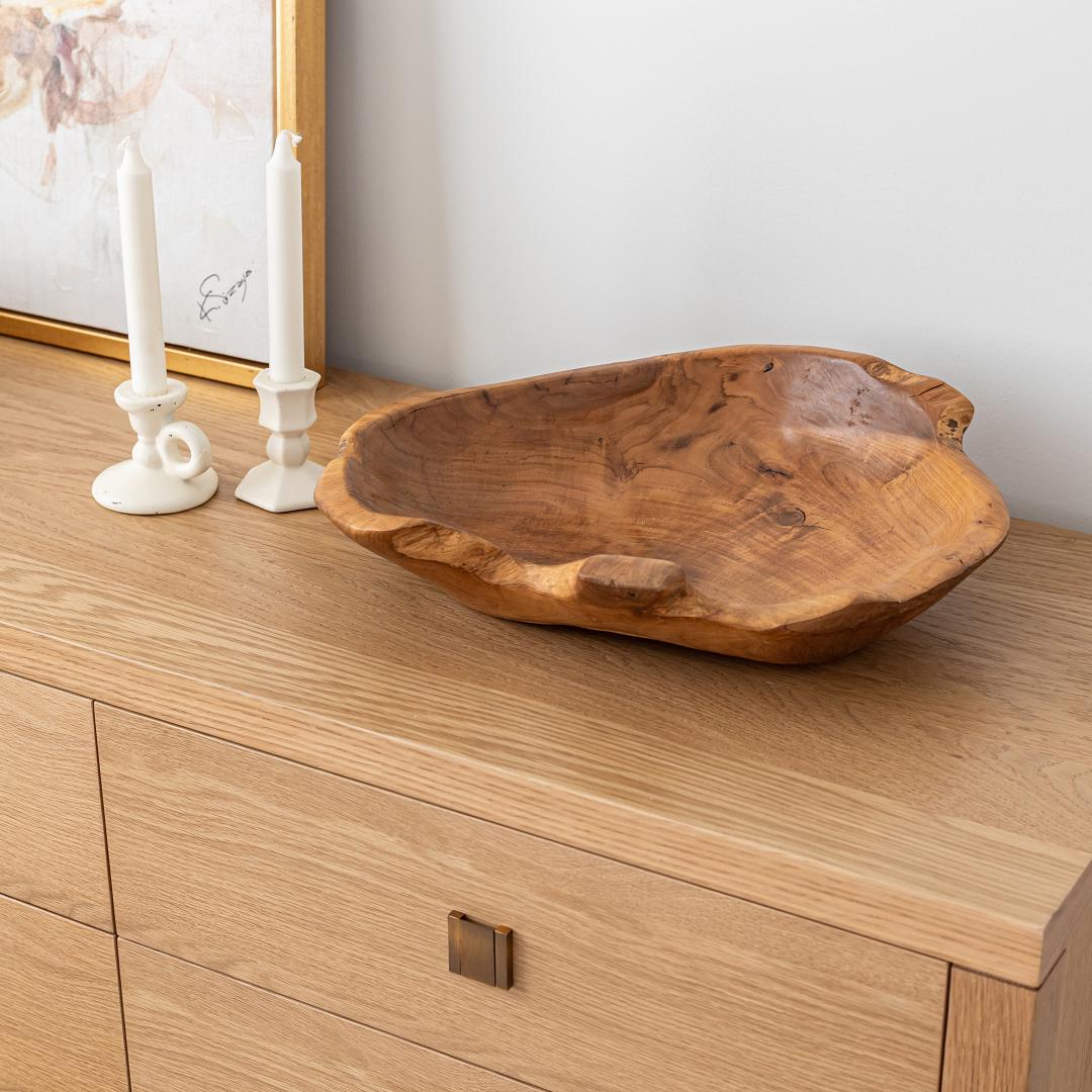 Wooden bowl on a wooden surface with candles in the background