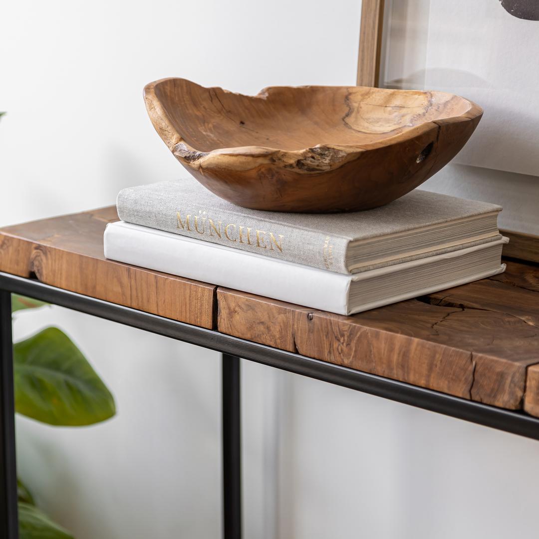 Wooden bowl on top of books on a wooden surface with a blurred background