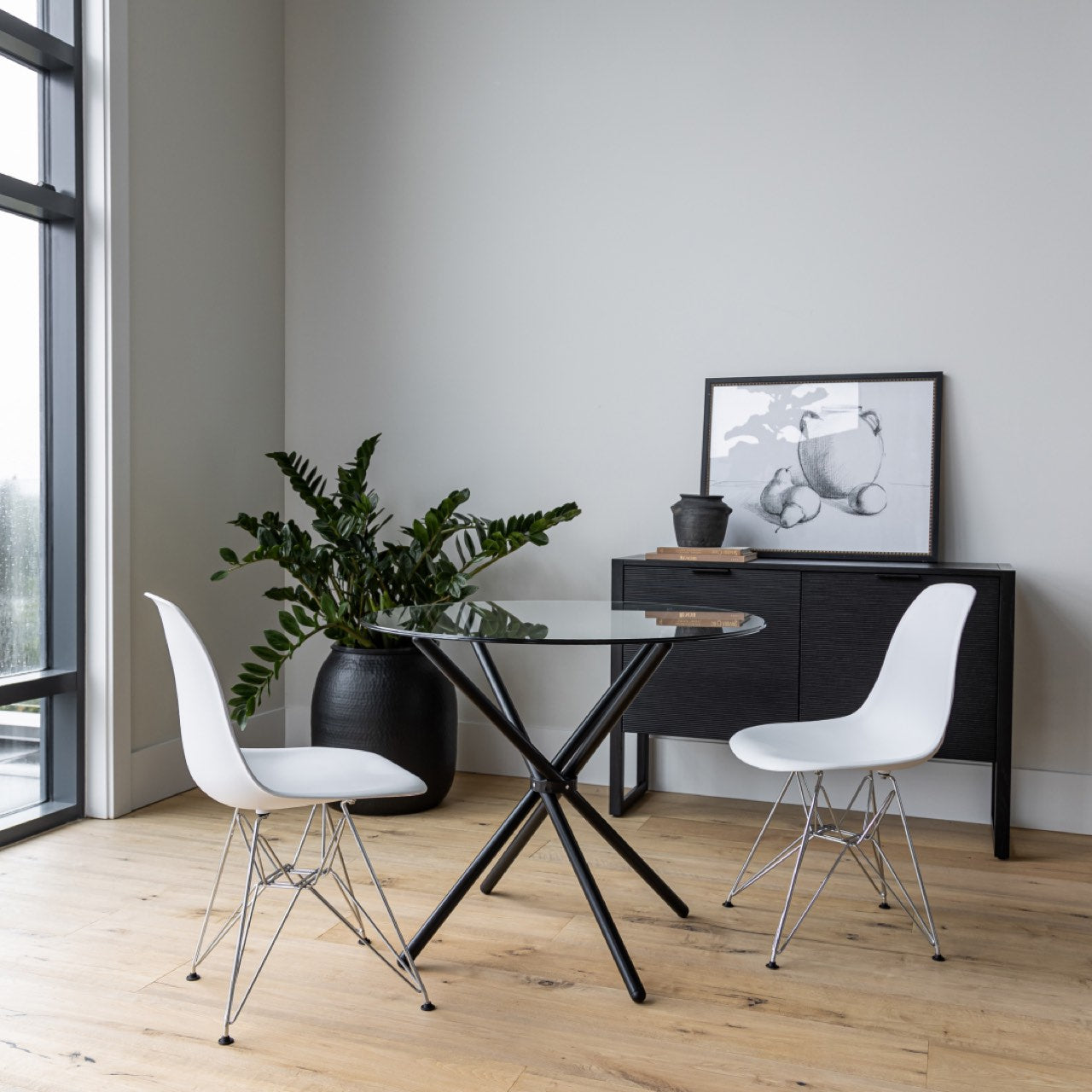 Modern dining area with a glass table and white chairs in a minimalistic room.