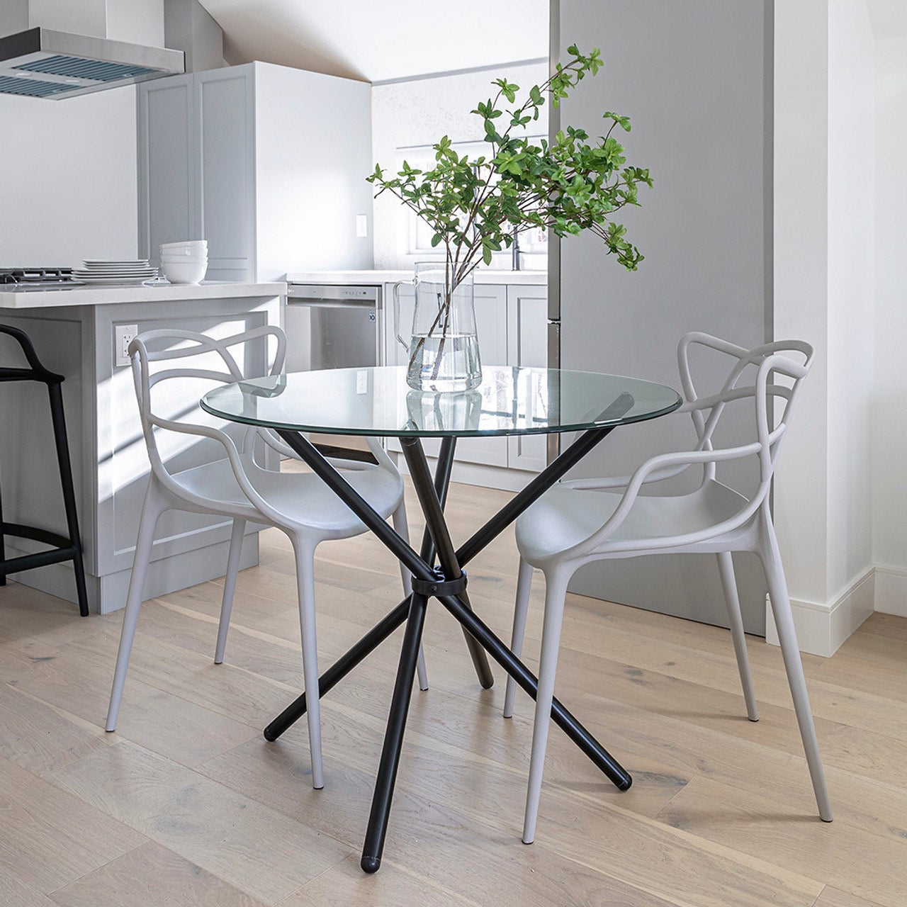 Modern kitchen with a glass dining table and white chairs.