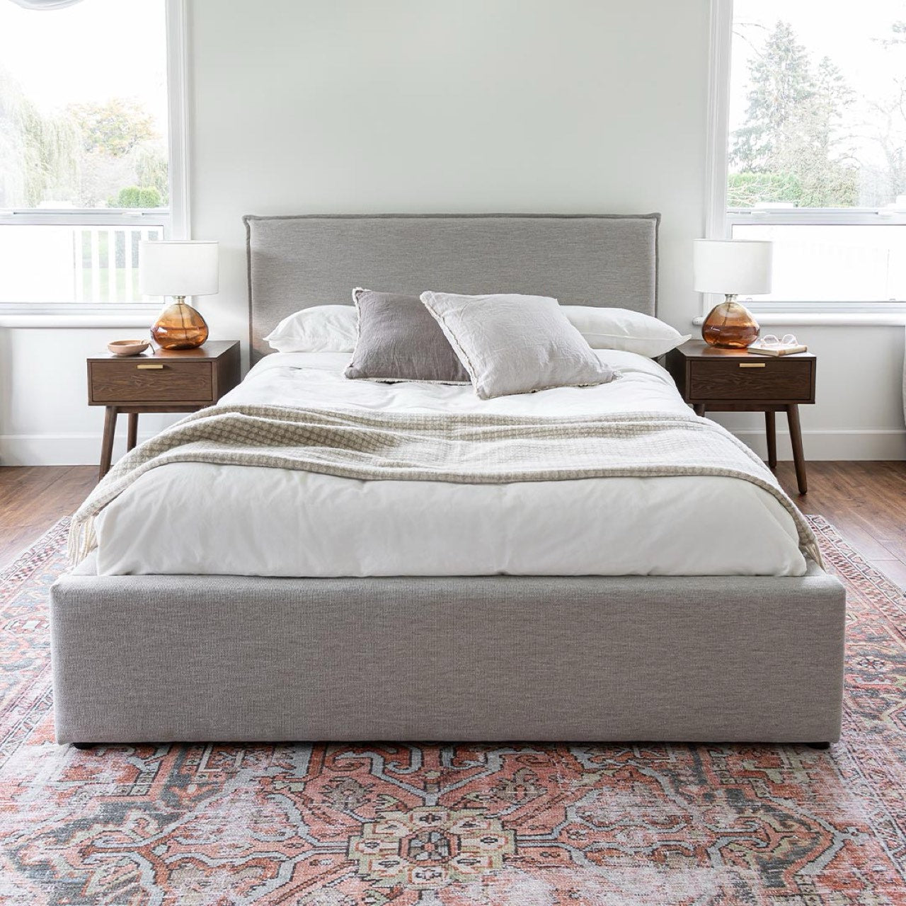 Gray upholstered bed with white mattress on a white background