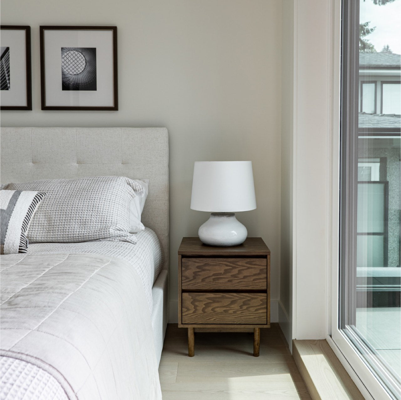 Bedroom with a bed featuring striped pillows and a plant next to it.