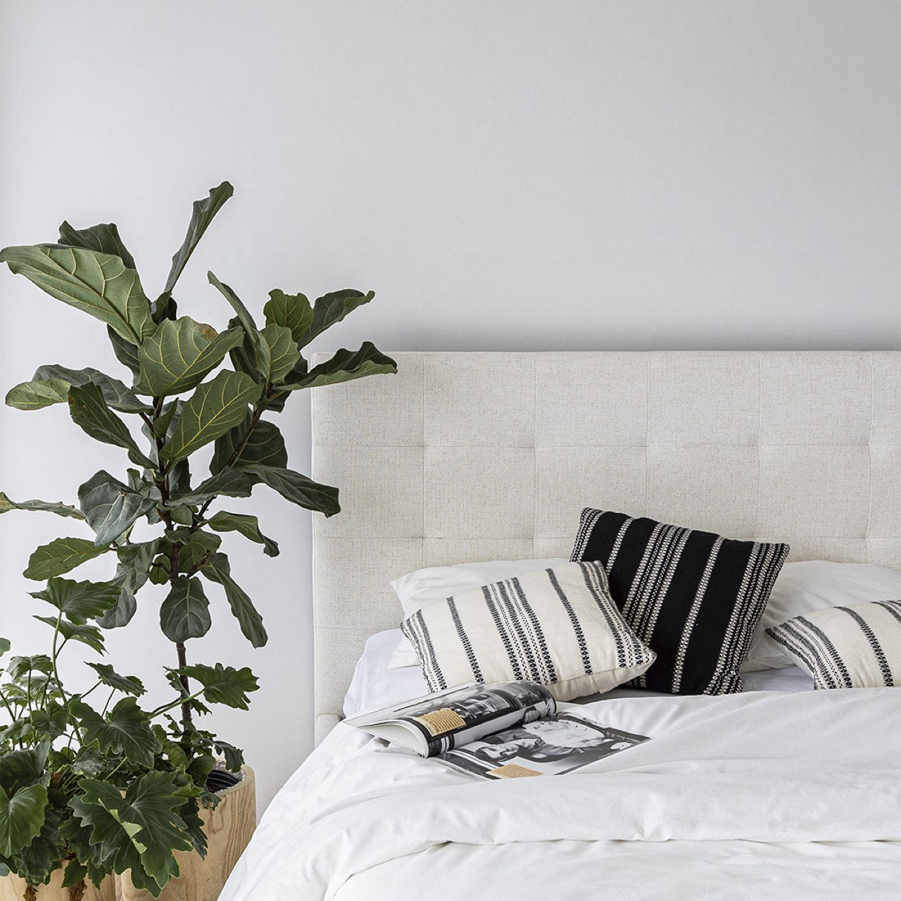 Bedroom with a bed featuring striped pillows and a plant next to it.