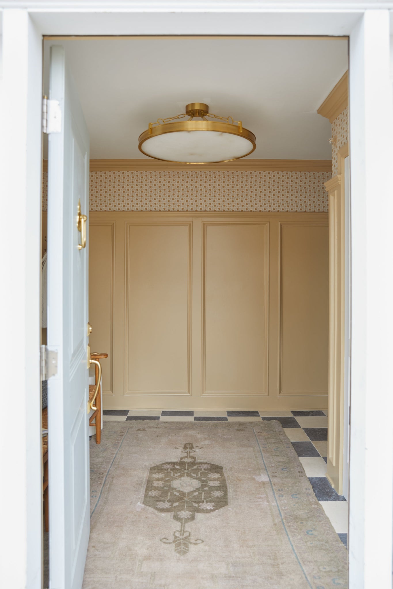 Kirby Chandelier 30" x 3.5" in aged brass styled in a two-story entry for warm, layered light at Laurie Yapp Home.