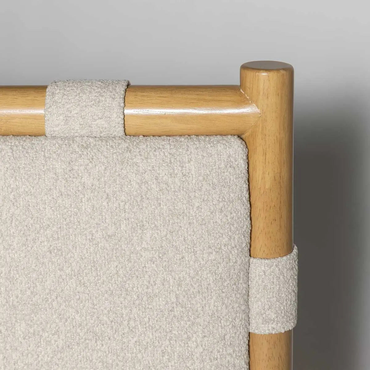 Close-up of a chair with wooden armrests and beige fabric on a gray background
