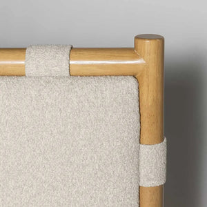 Close-up of a chair with wooden armrests and beige fabric on a gray background