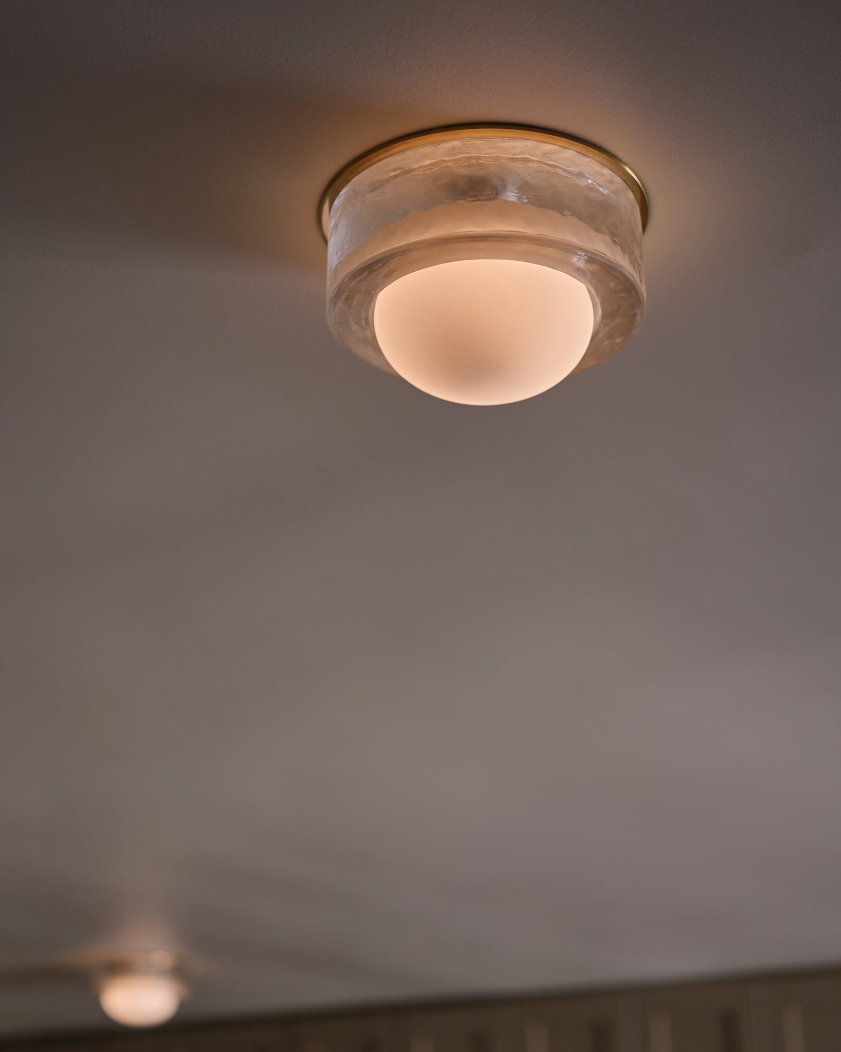 Mackay Wall Sconce 7.75" x 0" in aged brass styled in a warmly lit hallway for warm, layered light at Laurie Yapp Home.