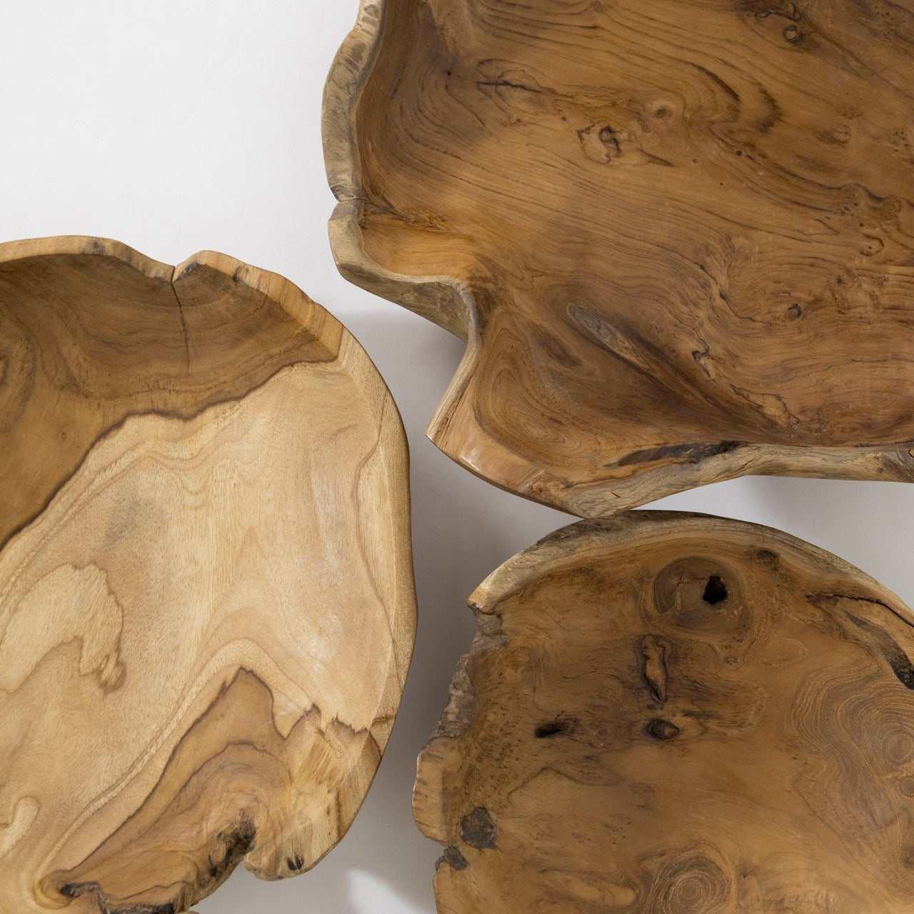 Three wooden bowls with natural, organic shapes on a white background