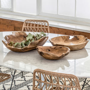 Three wooden bowls on a marble table with wicker chairs in a bright room.