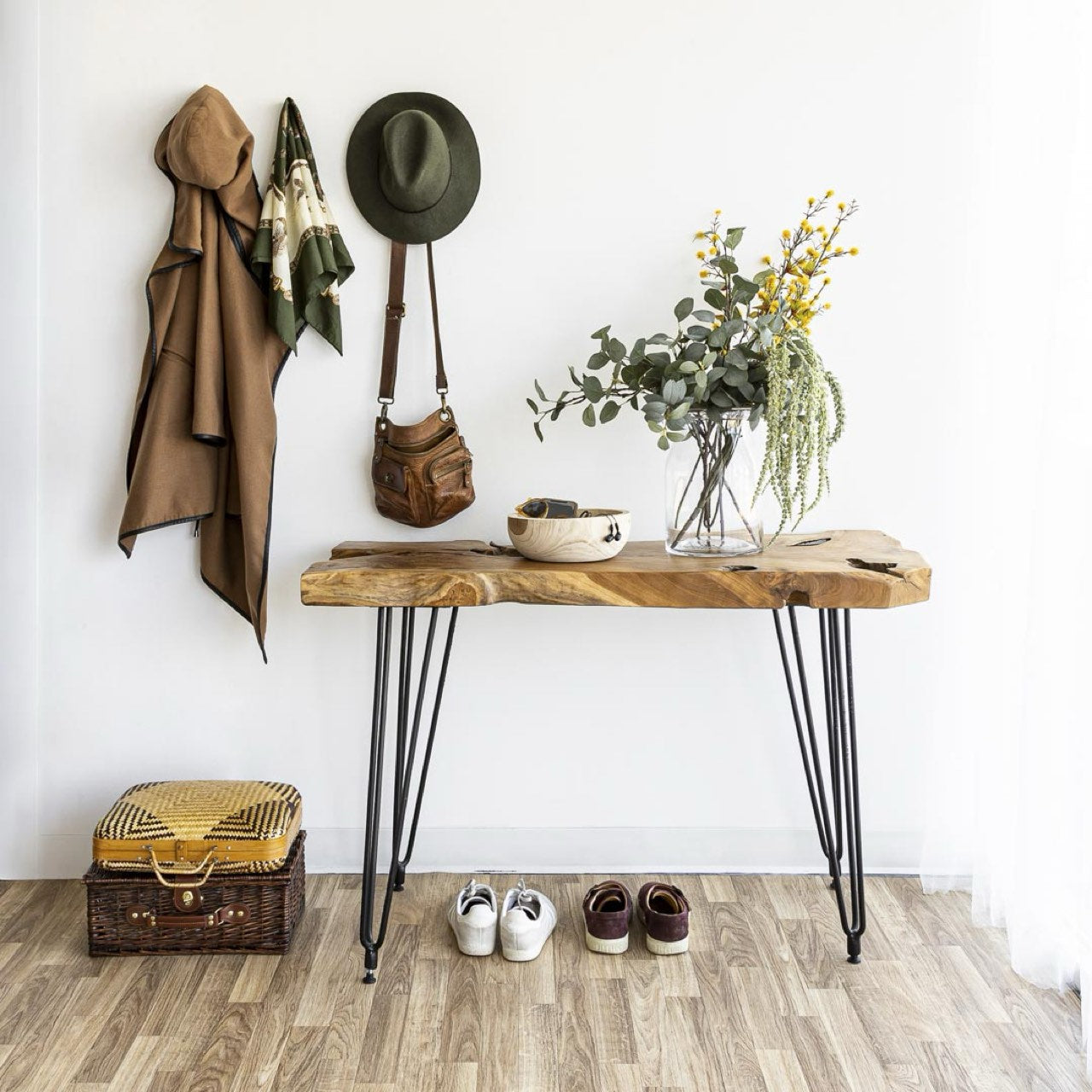 Wooden console table with hairpin legs in a room setting with shoes, a suitcase, and decorative items.