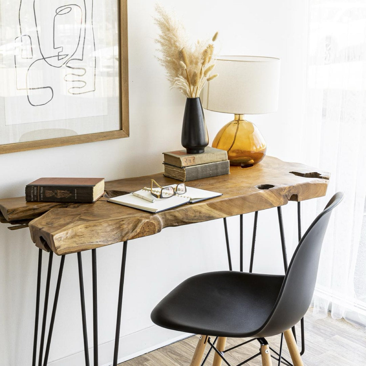Wooden console table with black chair against a white wall