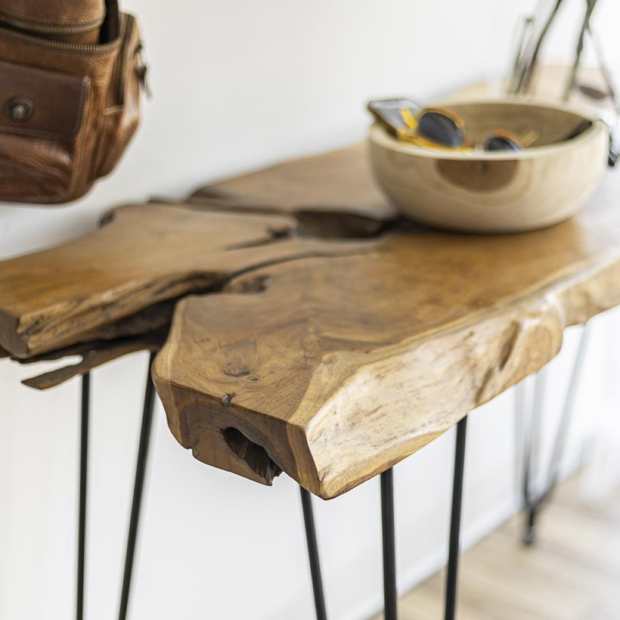 Wooden console table with a bowl on top against a white wall.